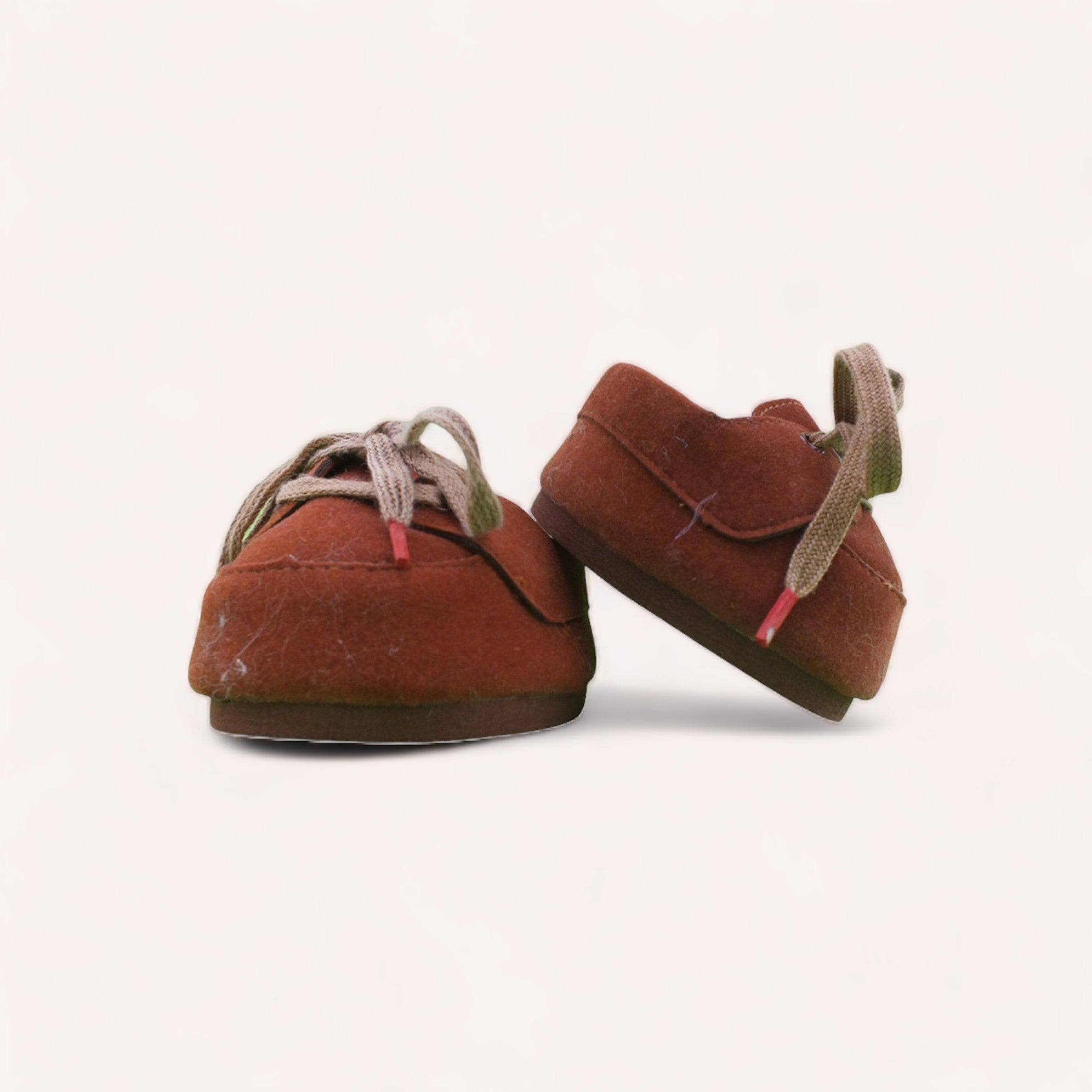 A pair of well-worn, tiny toddler Bear Brown Lace Up Boots from The Teddy Factory, with laces, standing on a white background, evoking a sense of nostalgia and the rapid pace of childhood growth.