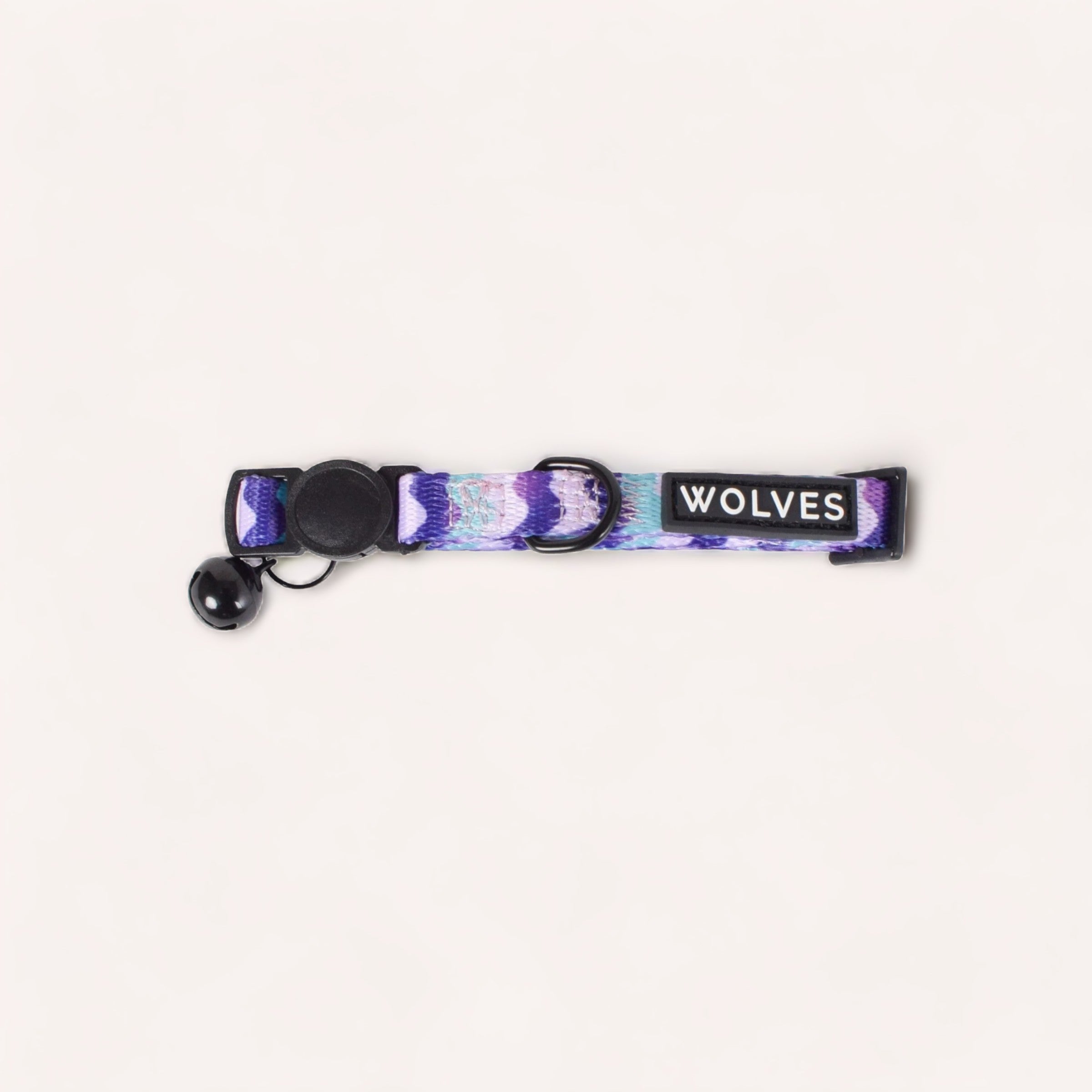 A Sulley Cat Collar by Wolves of Wellington with the word "Wolves of Wellington" printed on it, featuring a purple camouflage pattern, a black carabiner clip, and a detachable breakaway buckle.