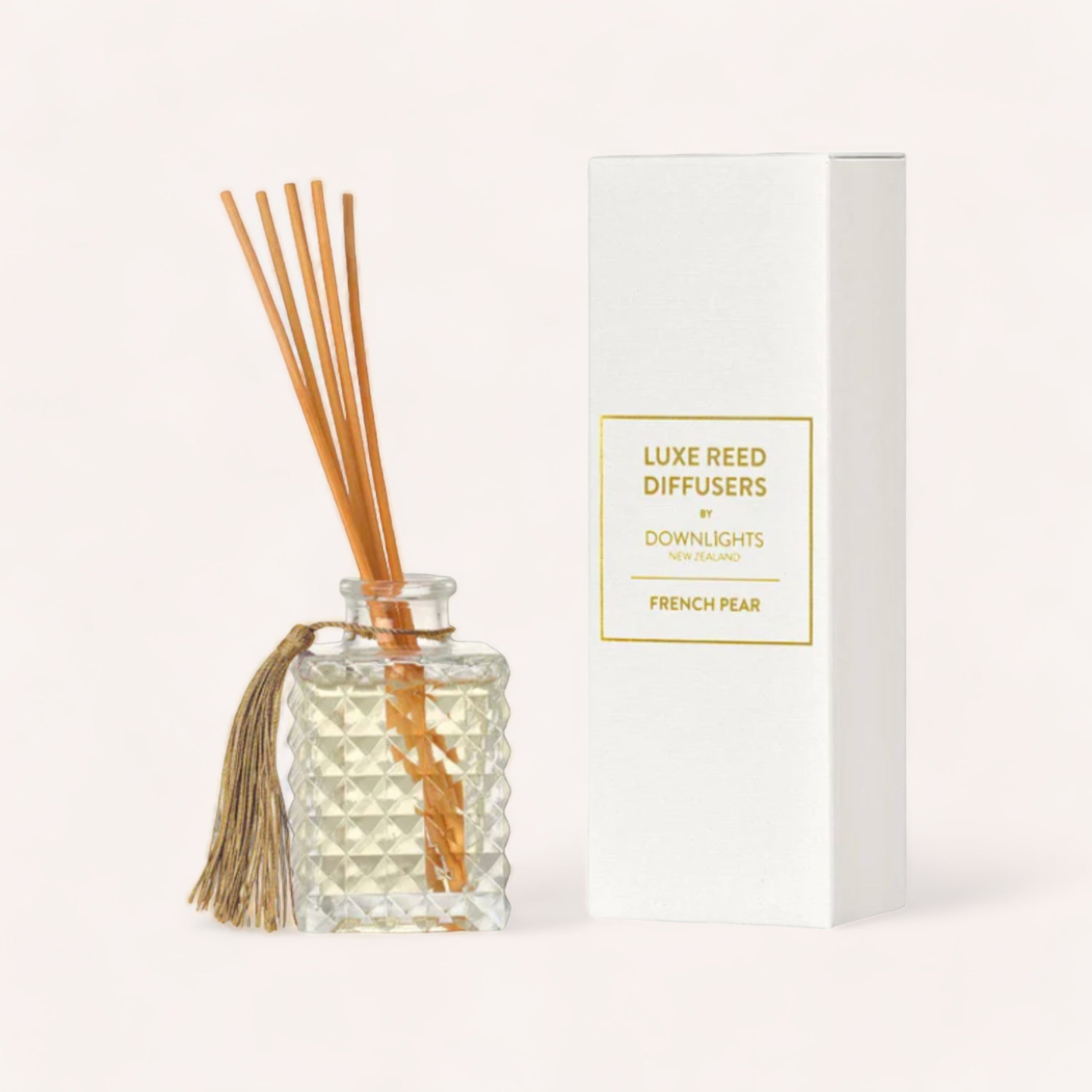 Elegant glass French Pear Diffuser by Downlights with a golden label accompanied by its packaging box, set against a neutral background, emitting a brandied sweet French pear scent.