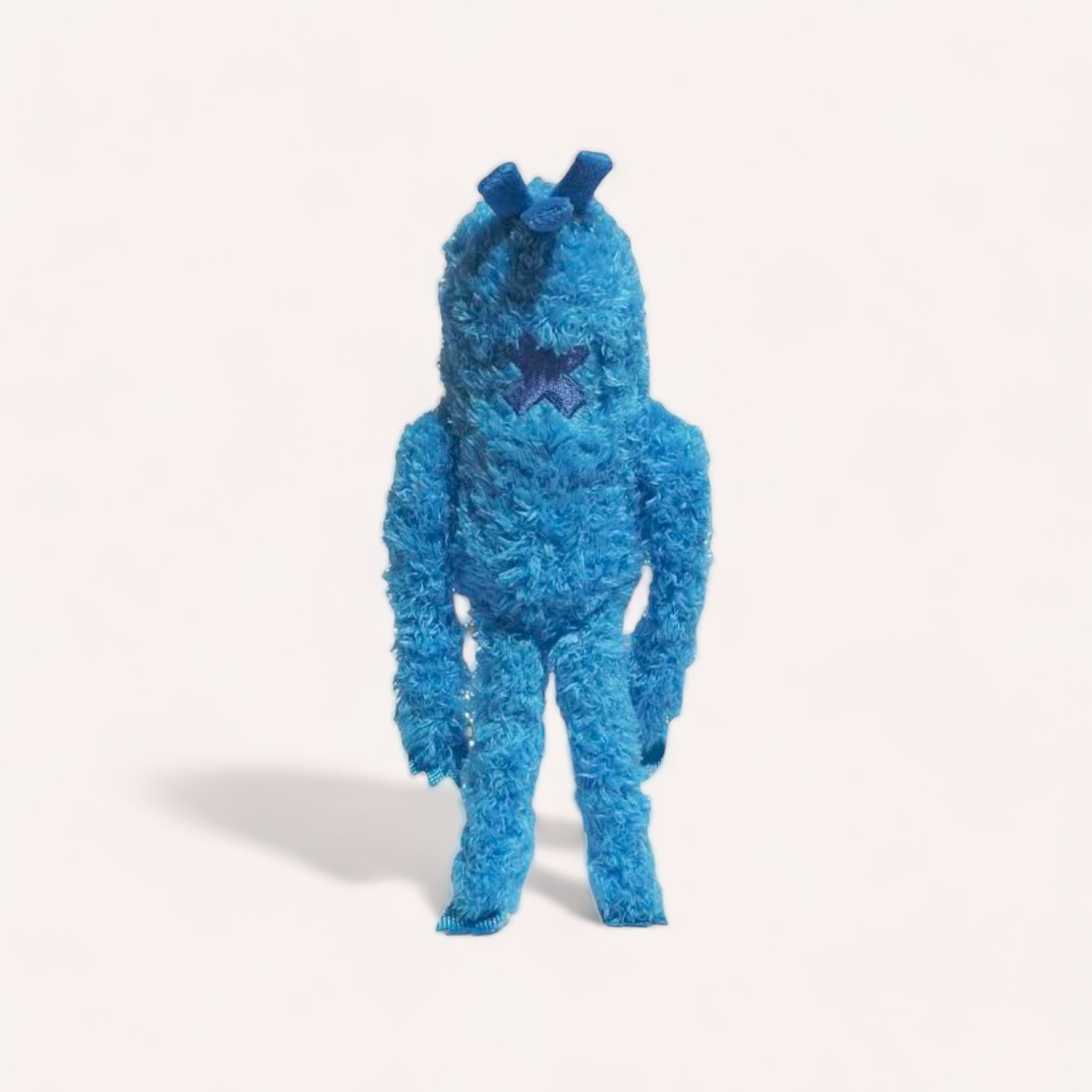 A person in a whimsical blue Blu Pet Toy by Zee.Dog plush toy costume with super soft fluffy fur and prominent eyes, standing against a white background.