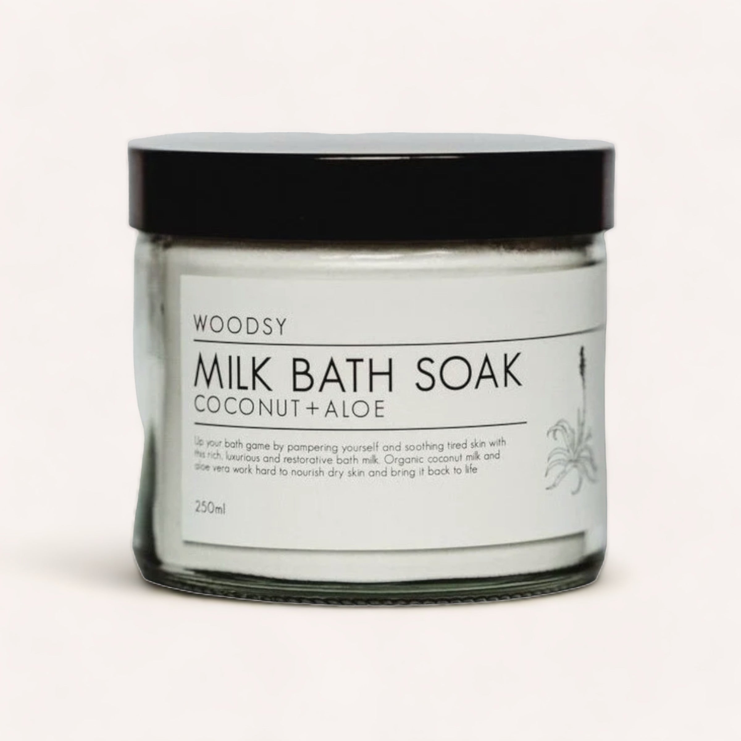 A jar of luxurious organic Milk Bath Soak - Coconut & Aloe by Woodsy Botanics against a neutral background.
