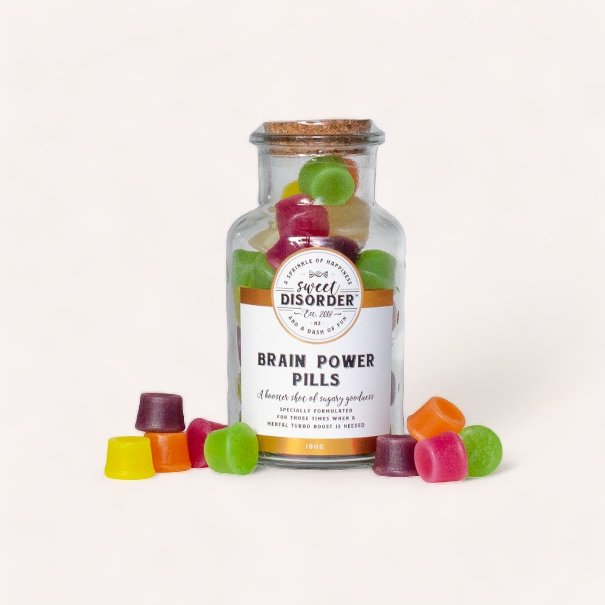 A whimsically labeled jar of Brain Power Pills Lollies by Sweet Disorder surrounded by colorful wine gums, suggesting a playful take on supplements.