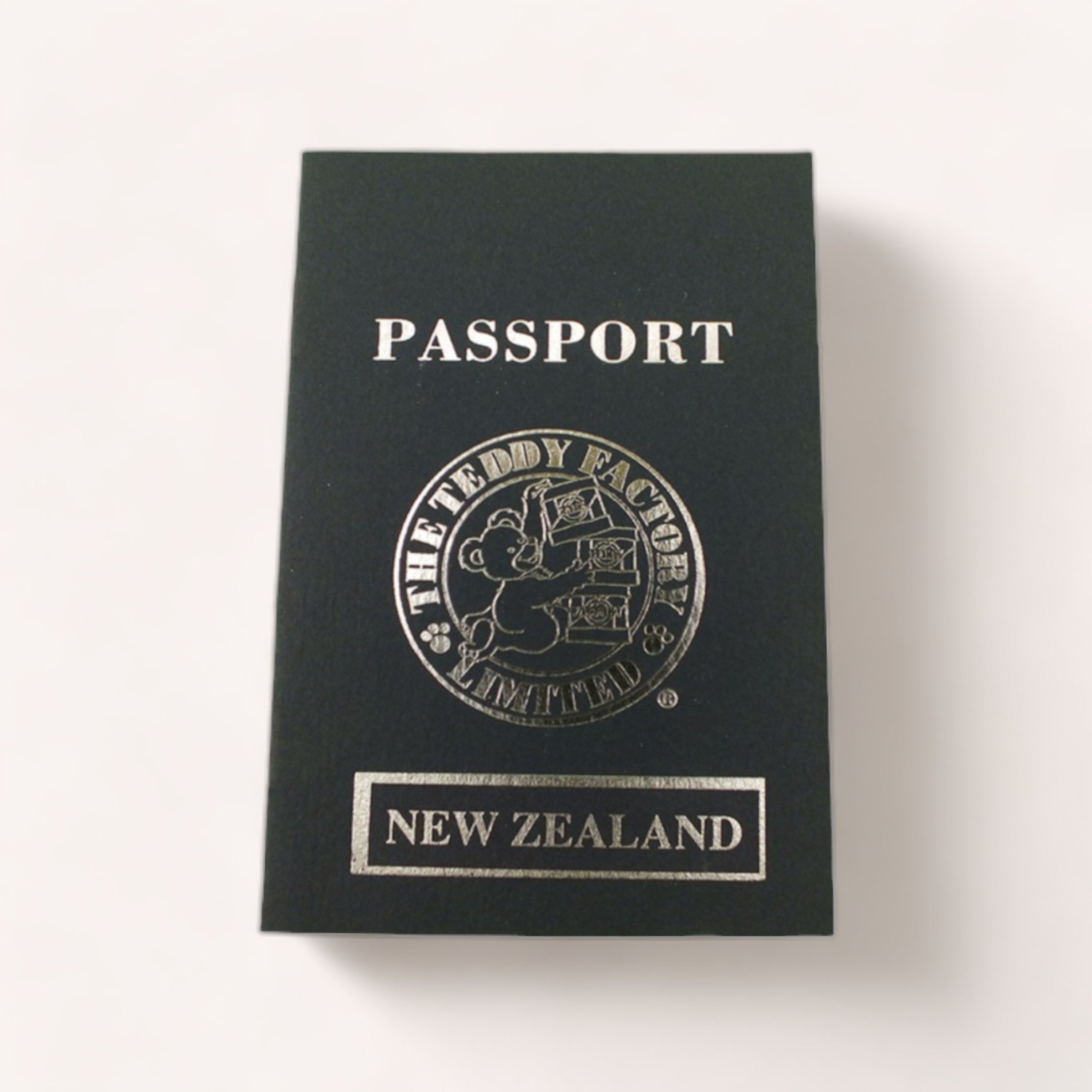 A Bear NZ Passport from The Teddy Factory adorned with travel stamps resting on a plain surface.