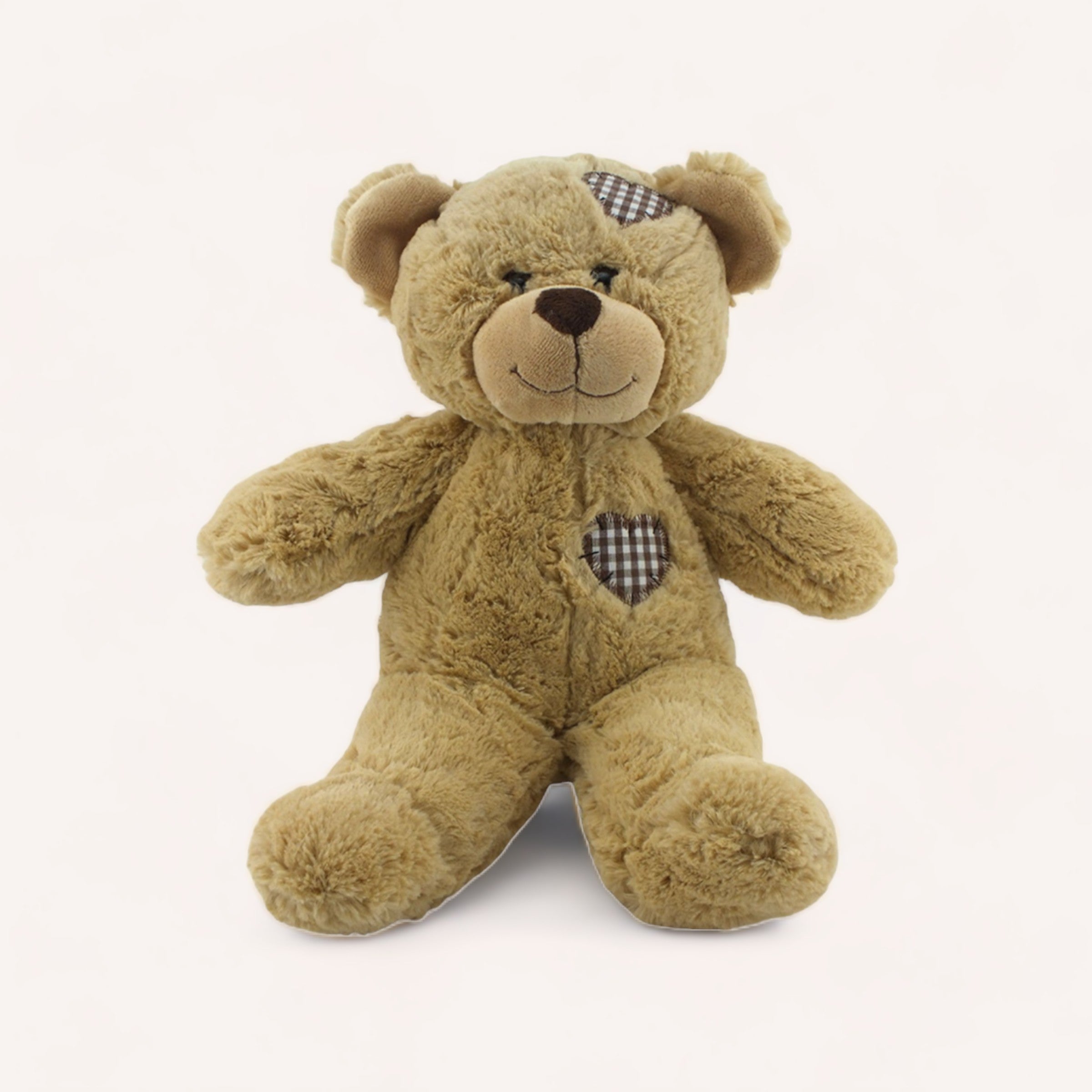 A plush friend with a checkered ear and Brown Patches, sitting against a white background is the Brown Patches Bear by The Teddy Factory.