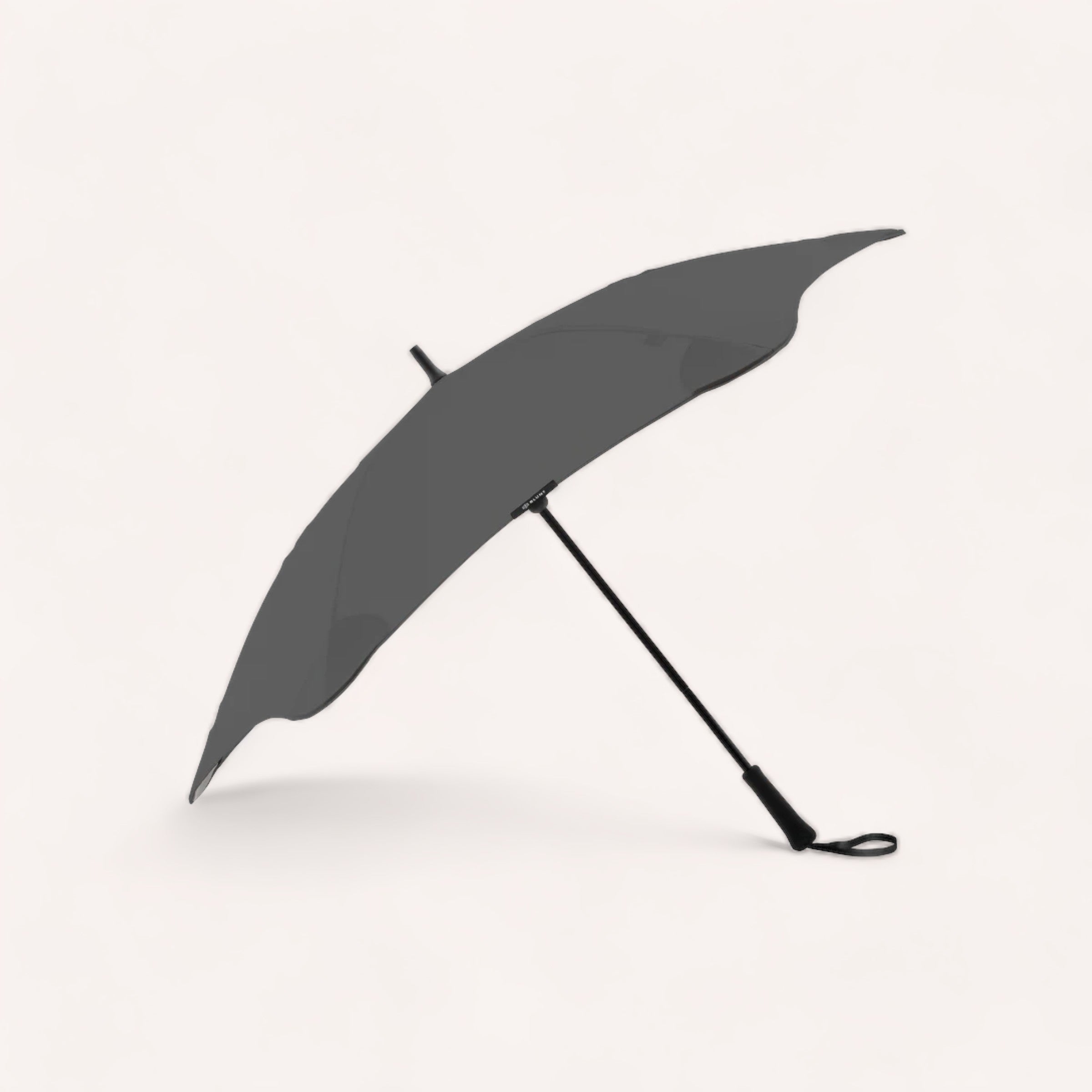 A black BLUNT Classic Umbrella Charcoal open and resting on its side against a white background.