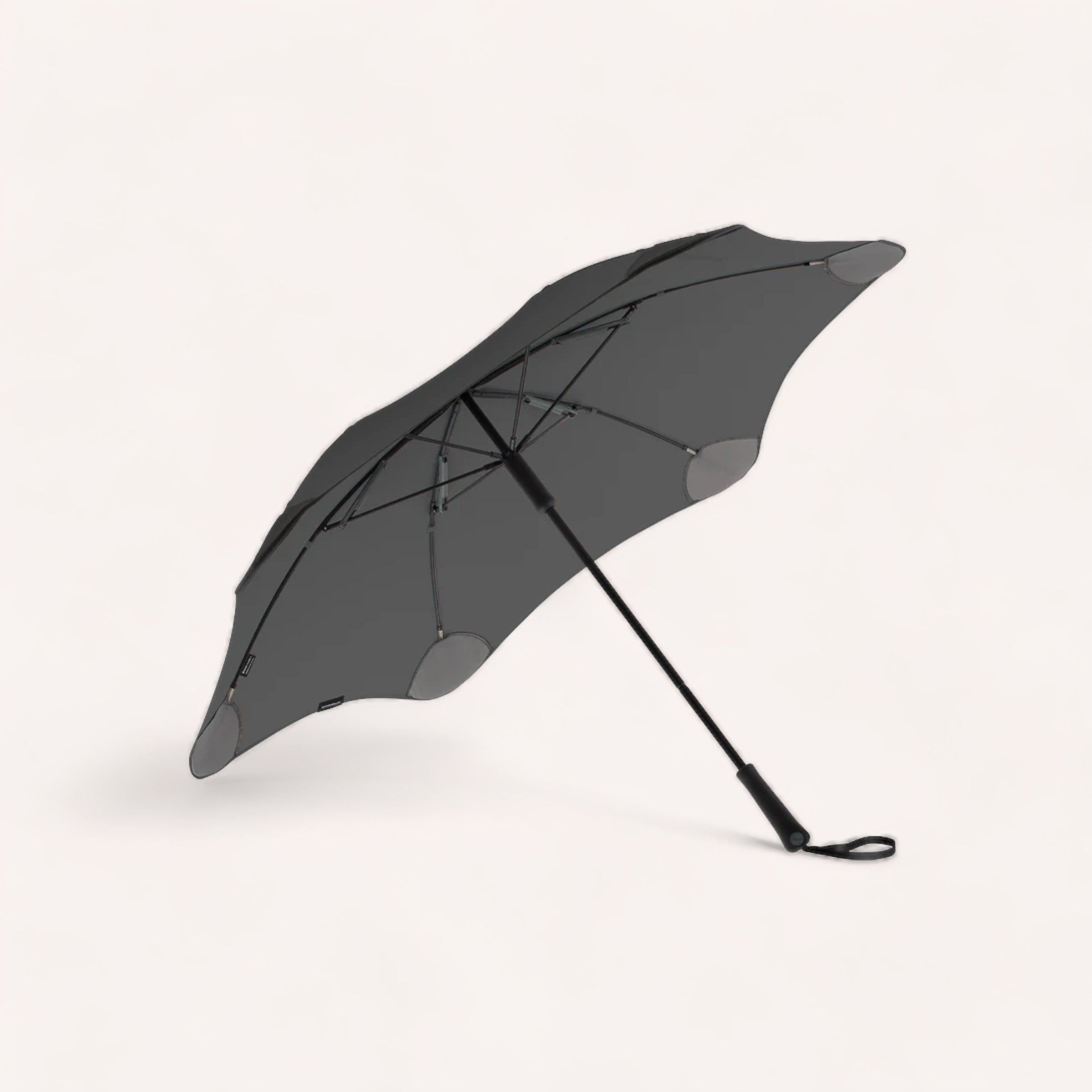 A black BLUNT classic compact umbrella opened and lying on its side against a white background.