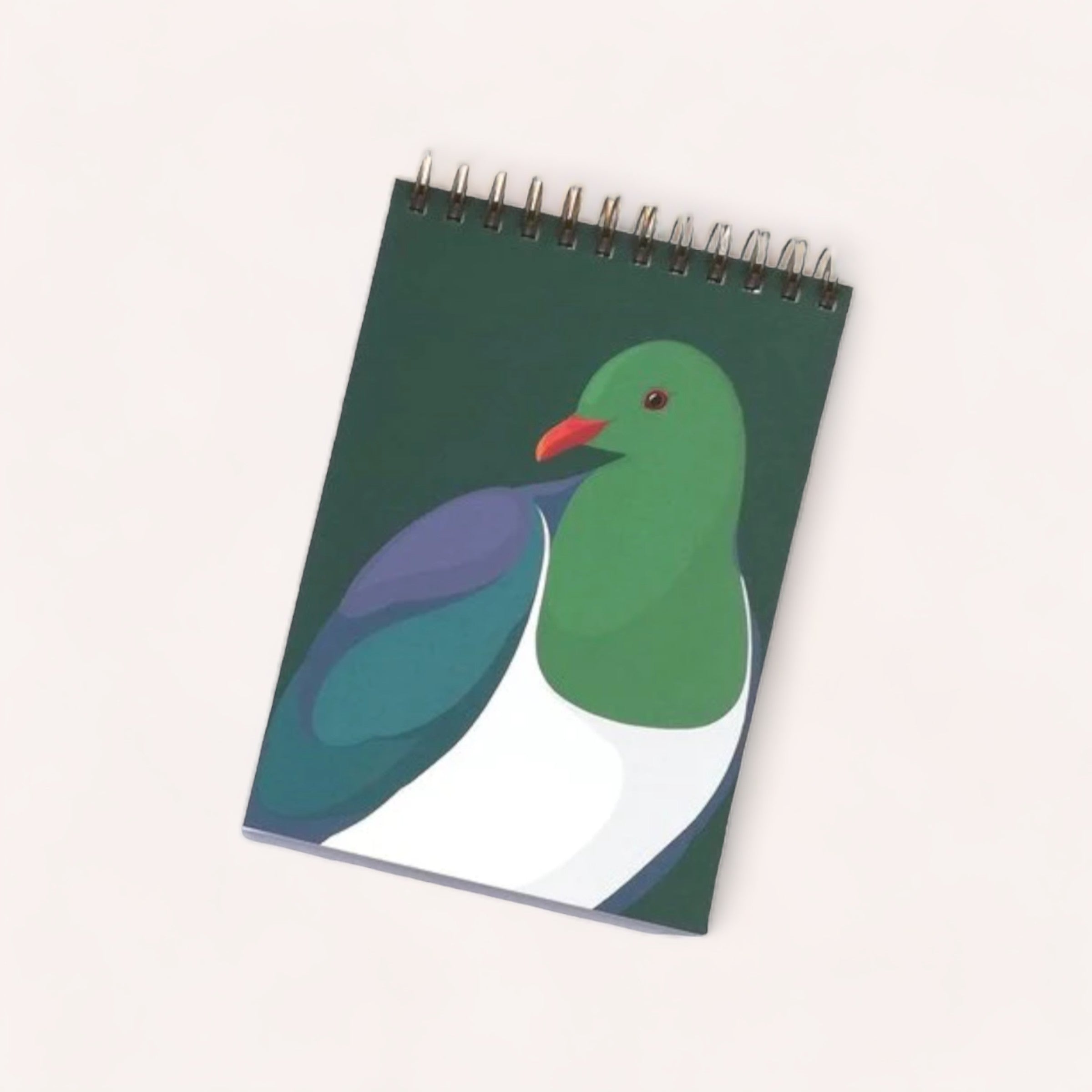 A Kereru Notebook by Hansby Design, featuring a spiral, unlined notebook with an illustrated cover showcasing a stylized green pigeon against a dark background.
