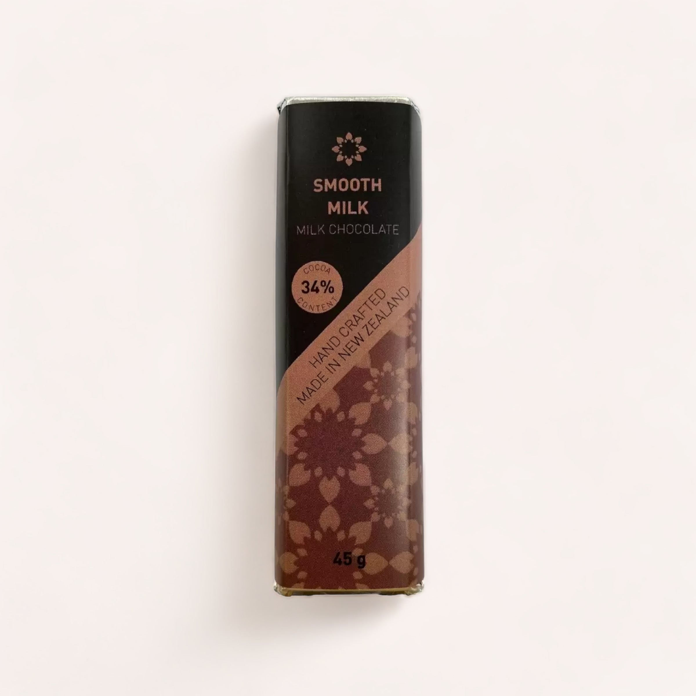 A Milk Chocolate bar by Chocolate Traders of smooth milk chocolate with elegant floral-patterned packaging, highlighting that it's handcrafted and contains 34% cocoa, weighing 45g.