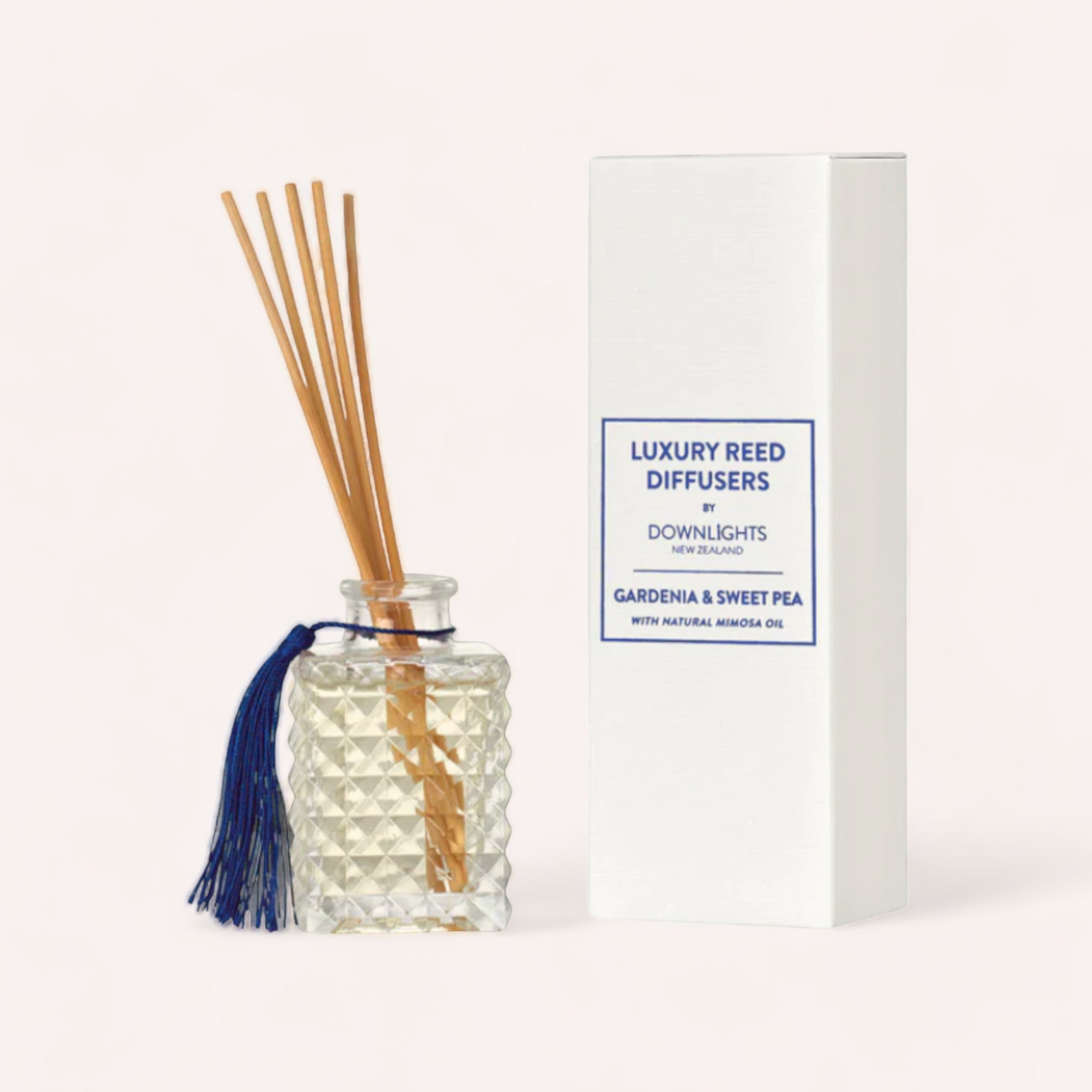 A luxury reed diffuser from Downlights, the Gardenia & Sweet Pea Diffuser with a geometric patterned glass container, featuring reeds inserted for fragrance dispersion, accompanied by a sleek white box labeled with "gardenia & sweet pea".