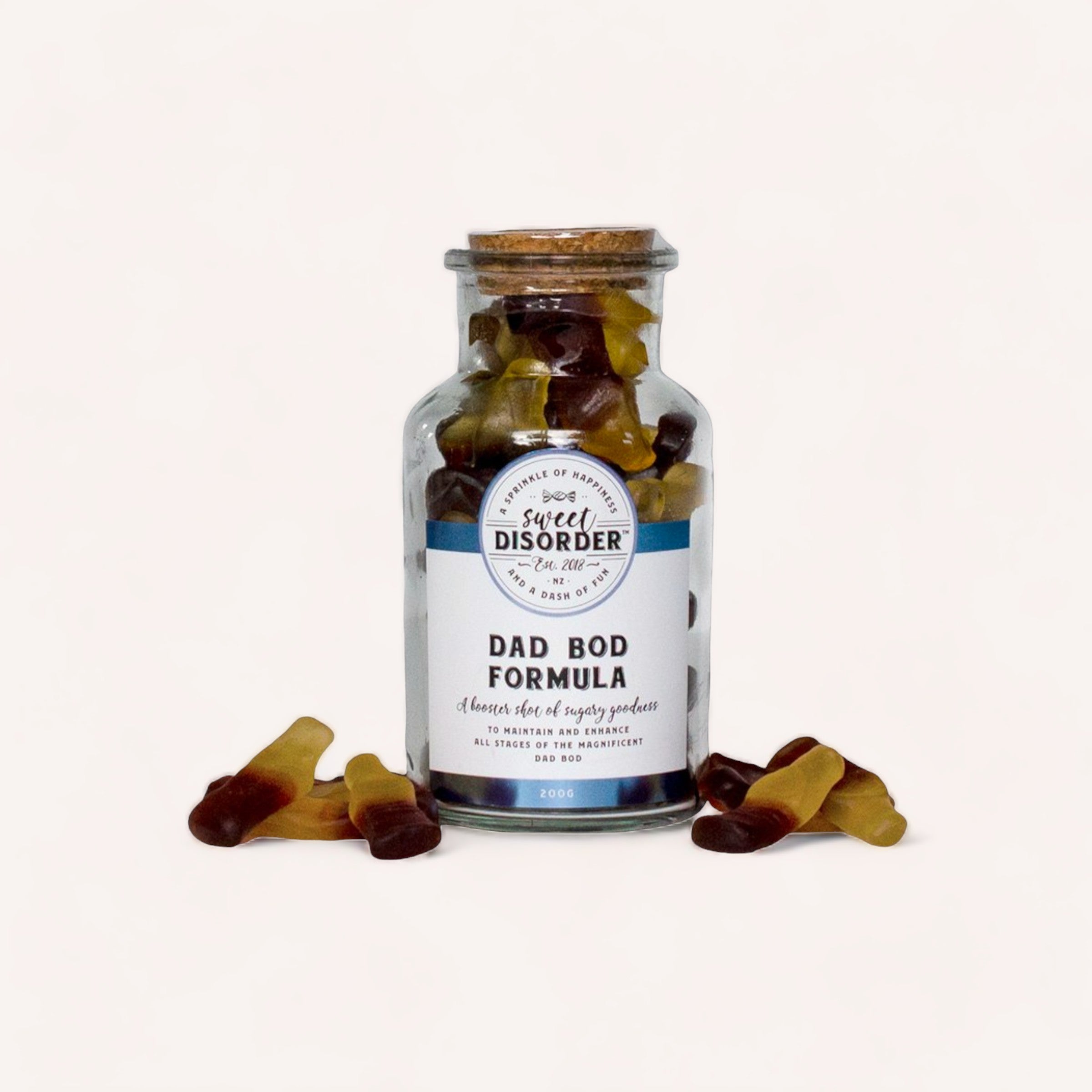 A jar labeled "Dad Bod Formula Lollies" by Sweet Disorder, filled with cola flavoured gummy bear candies, playfully suggesting a cheeky health supplement for achieving a relaxed physique.