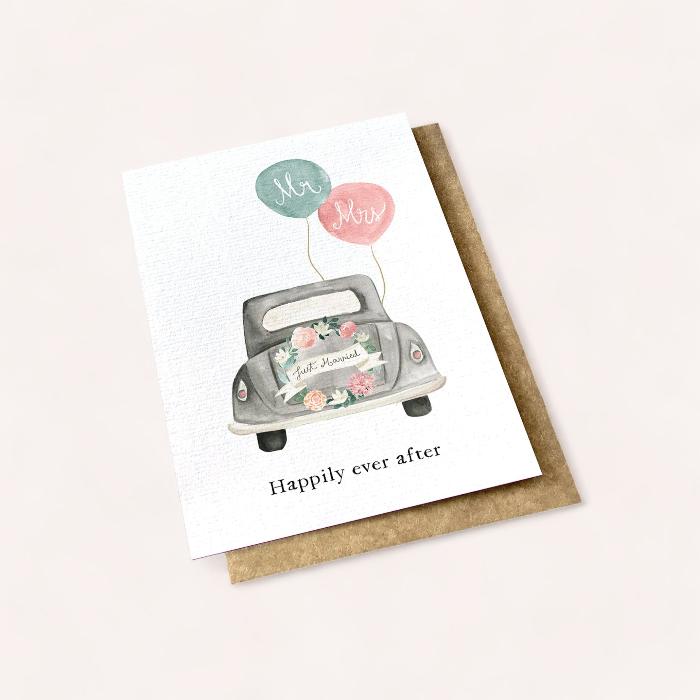 A charming Happily Ever After card by Ink Bomb featuring an illustration of a vintage car adorned with a floral arrangement and "just married" sign, complemented by "mr. & mrs." balloons above, and a sweet message