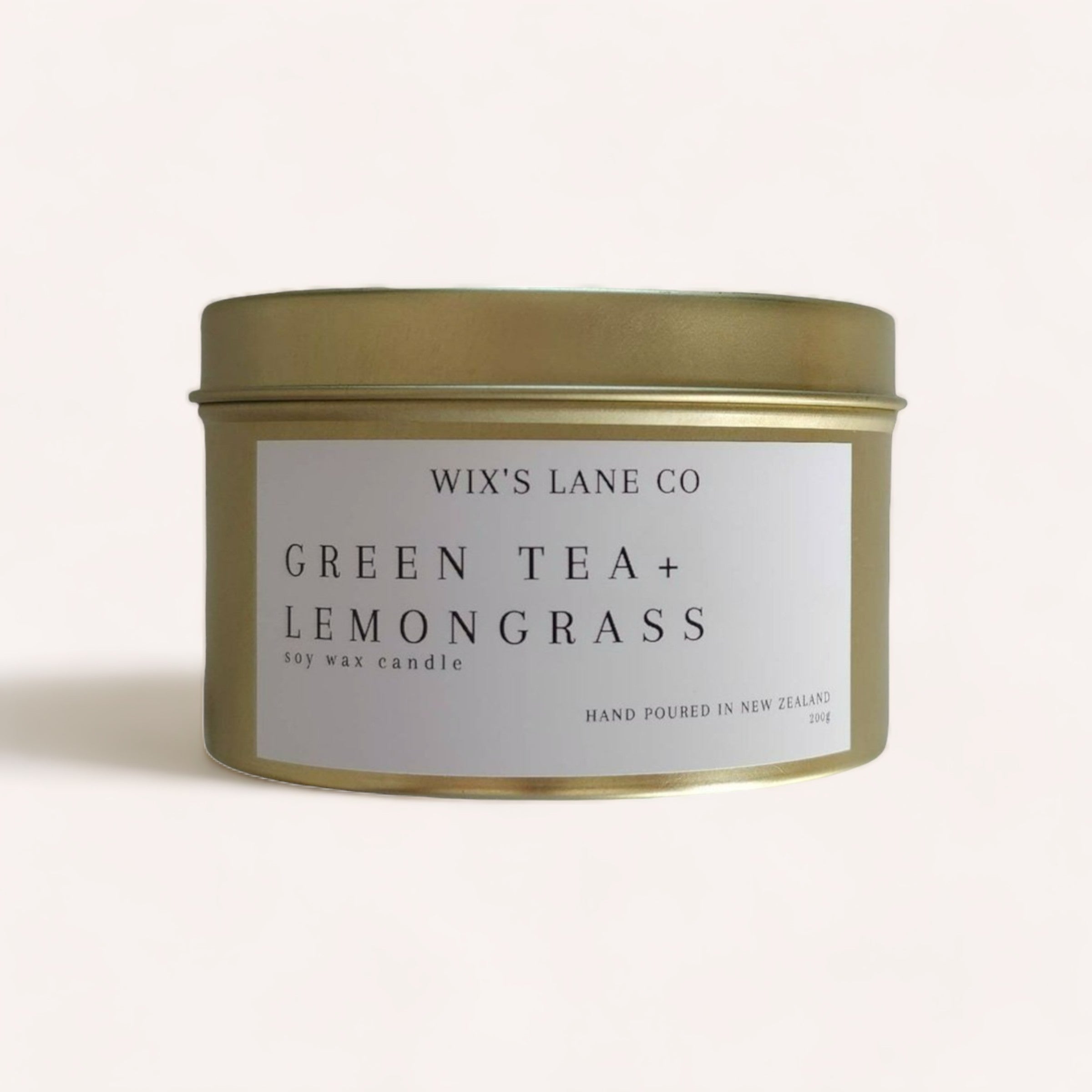 A minimalist-designed Green Tea + Lemongrass Candle labeled "green tea + lemongrass scent, soy wax candle, Product of New Zealand" by Wix's Lane Co, presented against a neutral background.