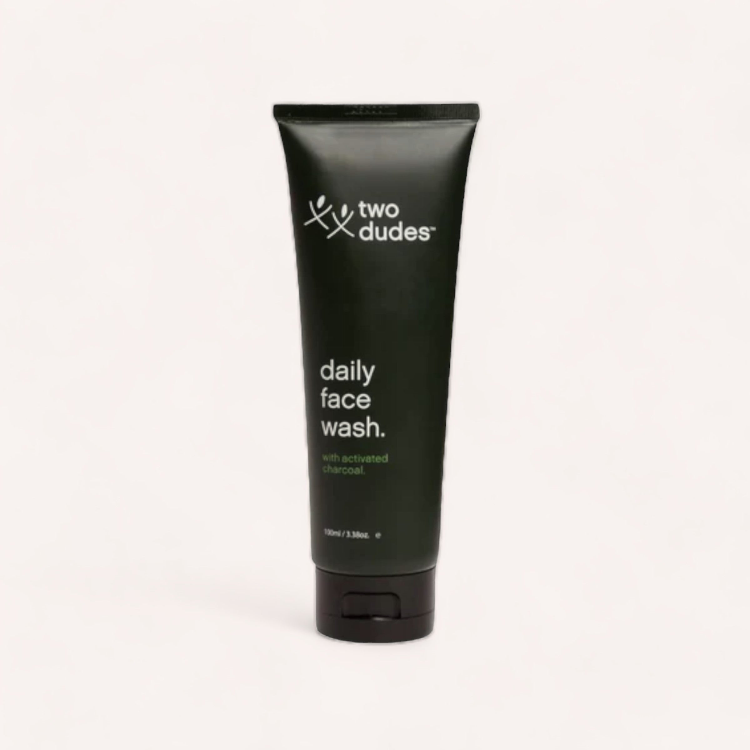 A sleek black tube of "Daily Face Wash by Two Dudes, suitable for all skin types" against a clean, light background.