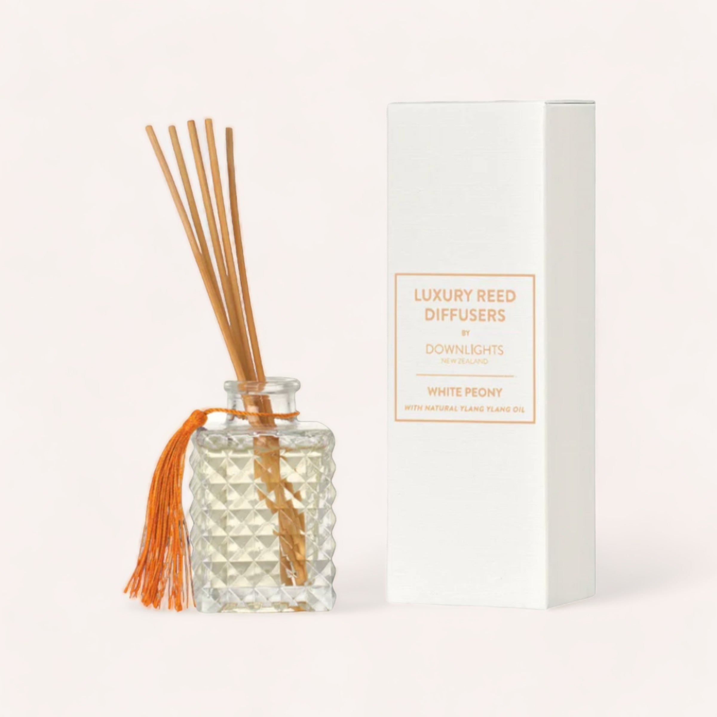 A luxury White Peony Diffuser by Downlights, with the scent of soft white peonies, accompanied by several reed sticks and packaged in an elegant white box.