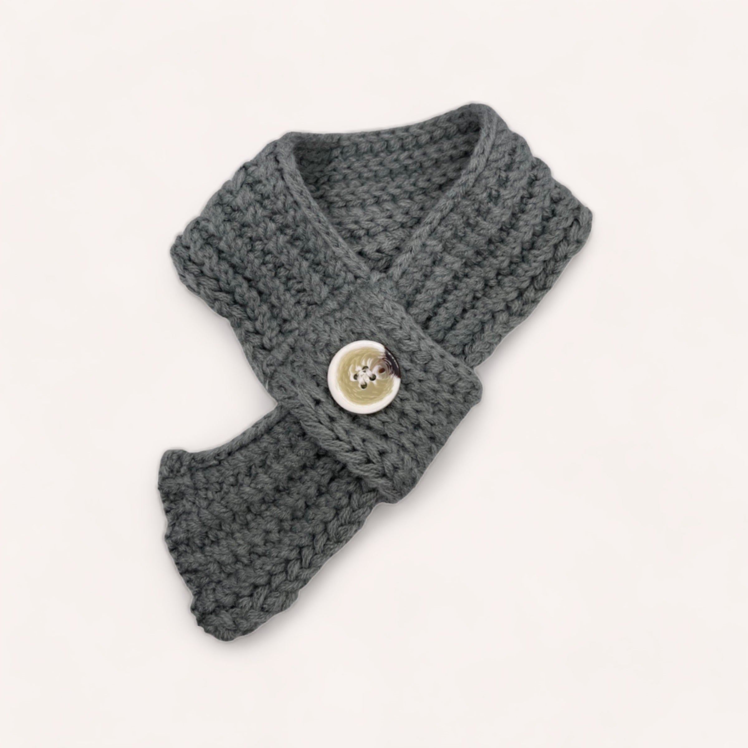 A gray, knitted Pet Scarf with a large button displayed on a white background, perfect as a pet winter accessory from giftbox co.