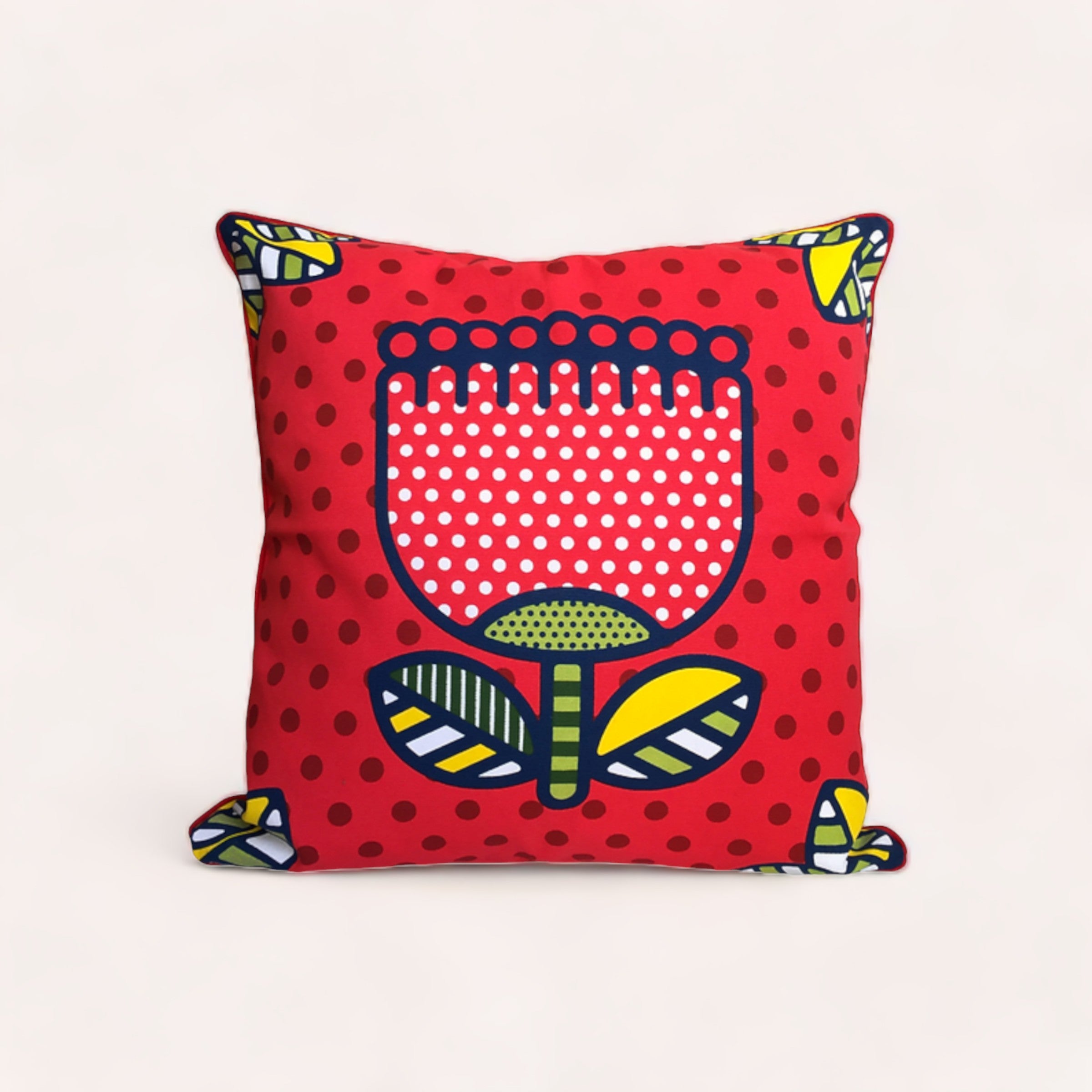 A vibrant red Pohutukawa Cushion Cover by Design by Leonard featuring a stylized illustration of a pohutukawa flower in a pop-art design, set against a dotted background, with playful tassel accents on the corners.