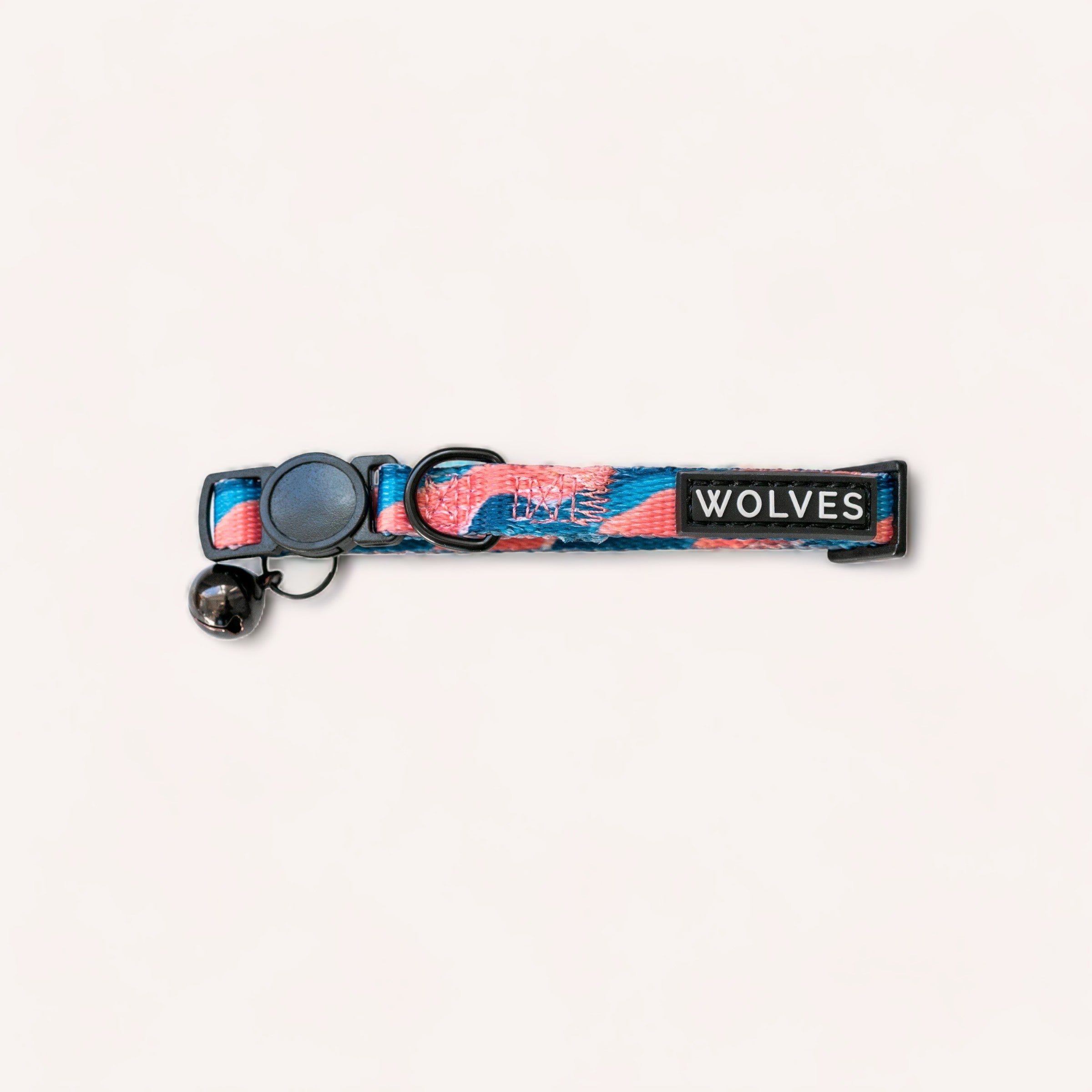 A colorful Dusk Cat Collar by Wolves of Wellington with "love wolves" text in navy, pink, and earthy tones, featuring an adjustable strap, a breakaway buckle, and a d-ring for leash attachment, displayed on.