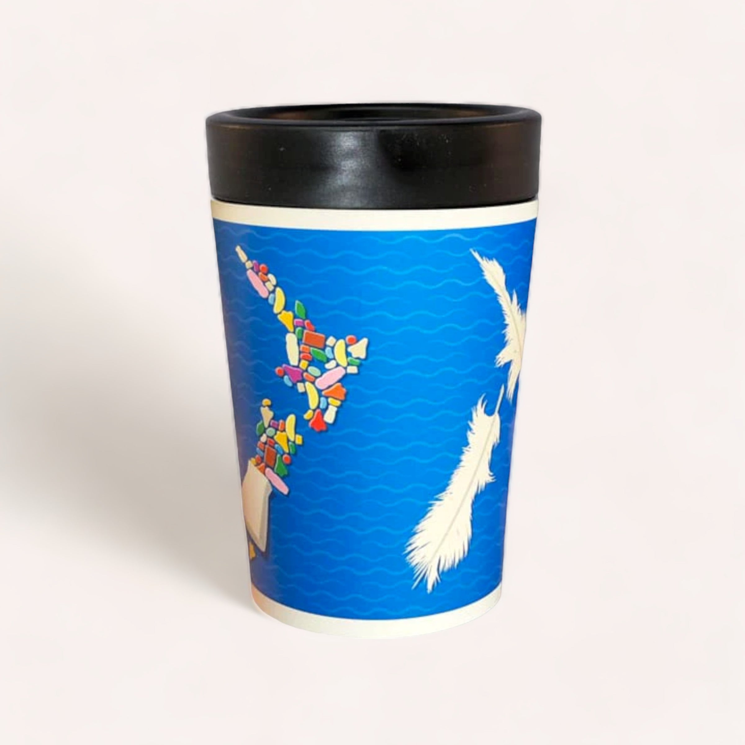A Cuppacoffeecup New Zealand Coffee Mug with a unique blue, ocean-themed design featuring vibrant fish assembled from various colorful shapes, and delicate white feathers hovering against the rippling water pattern.