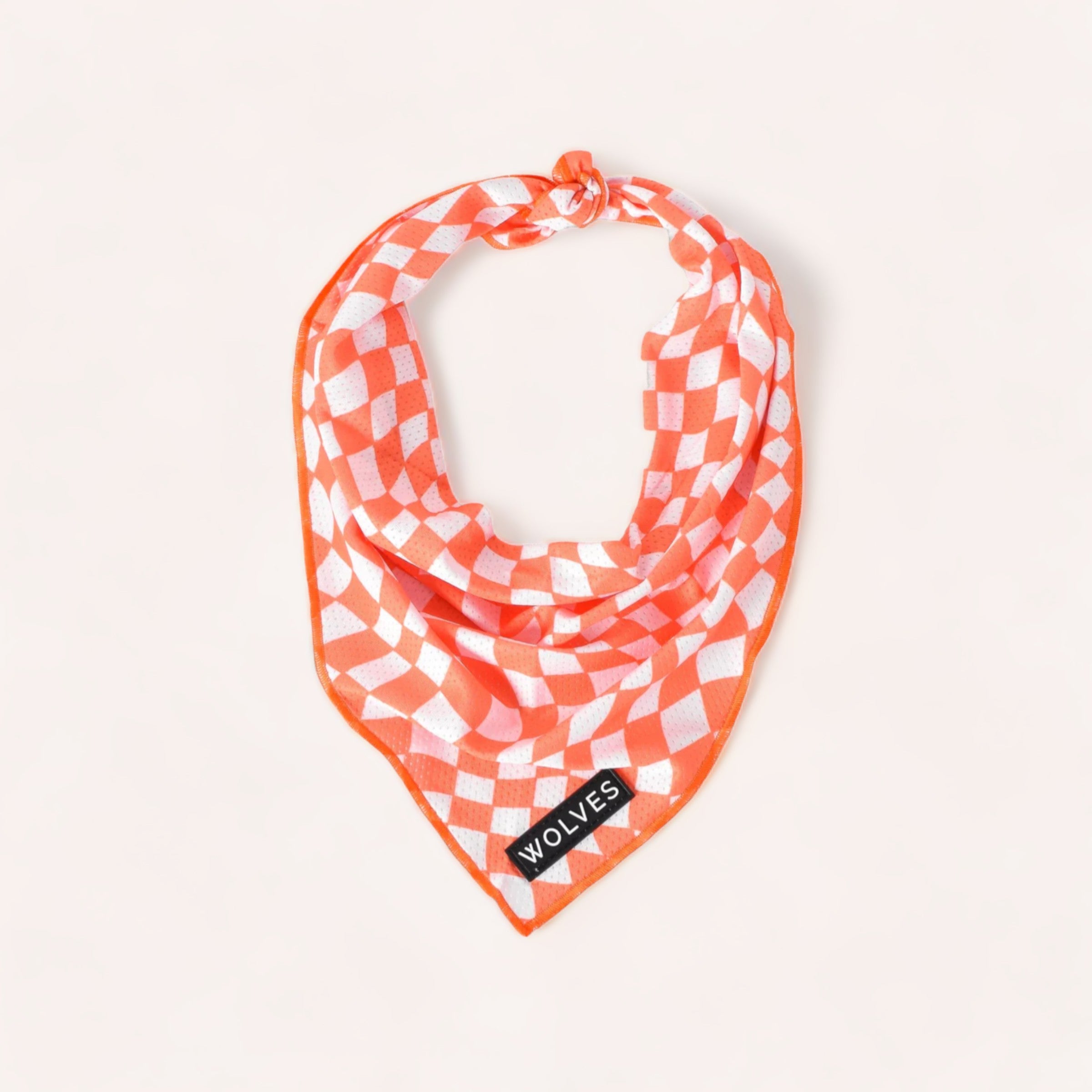 Orange and lightweight mesh material Benji Bandanas by Wolves of Wellington with the word "wolves" on a label, displayed on a plain background.