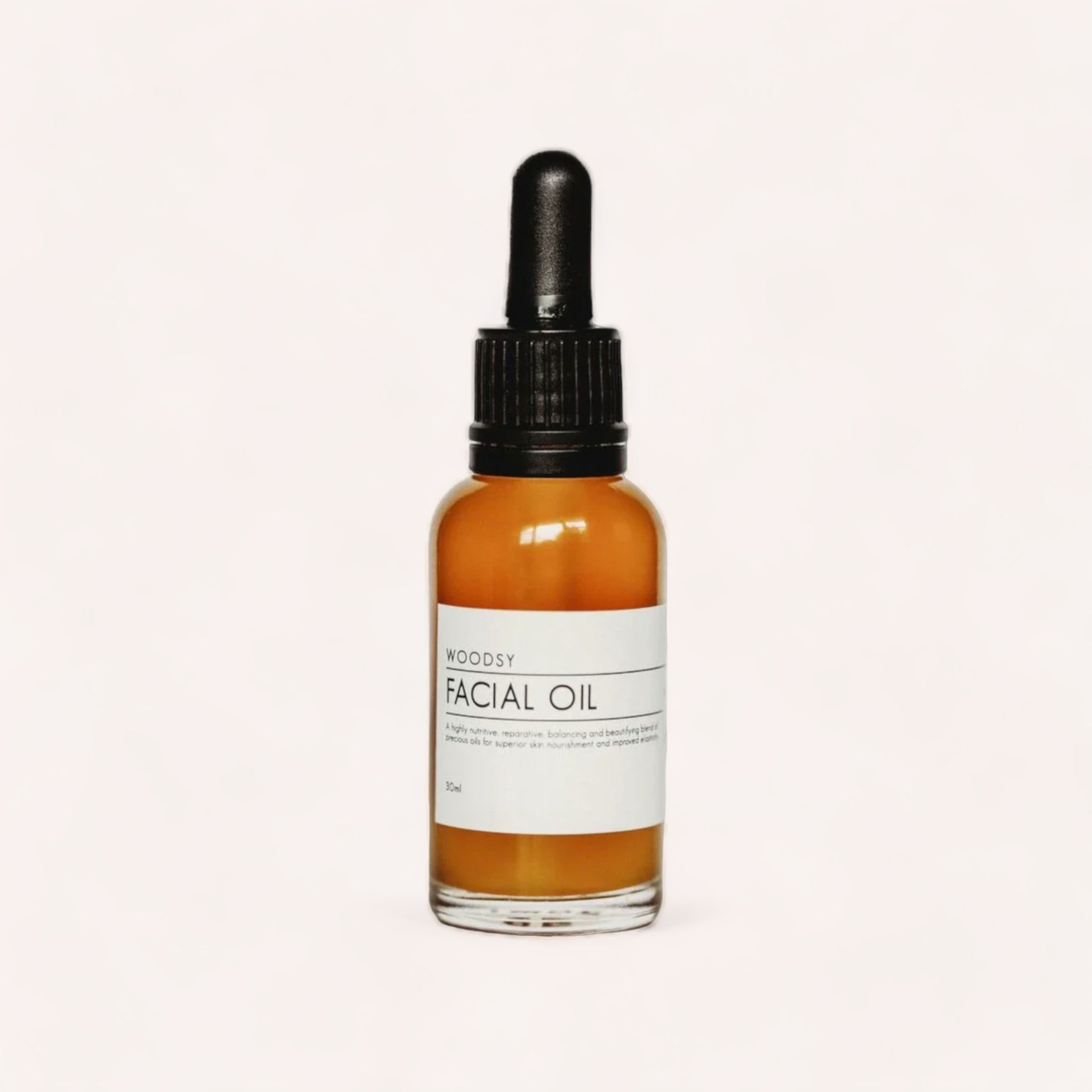 A dropper bottle of Facial Oil by Woodsy Botanics infused with hyaluronic acid, designed to address signs of ageing, features a "woodsy" label presented against a clean, white background.