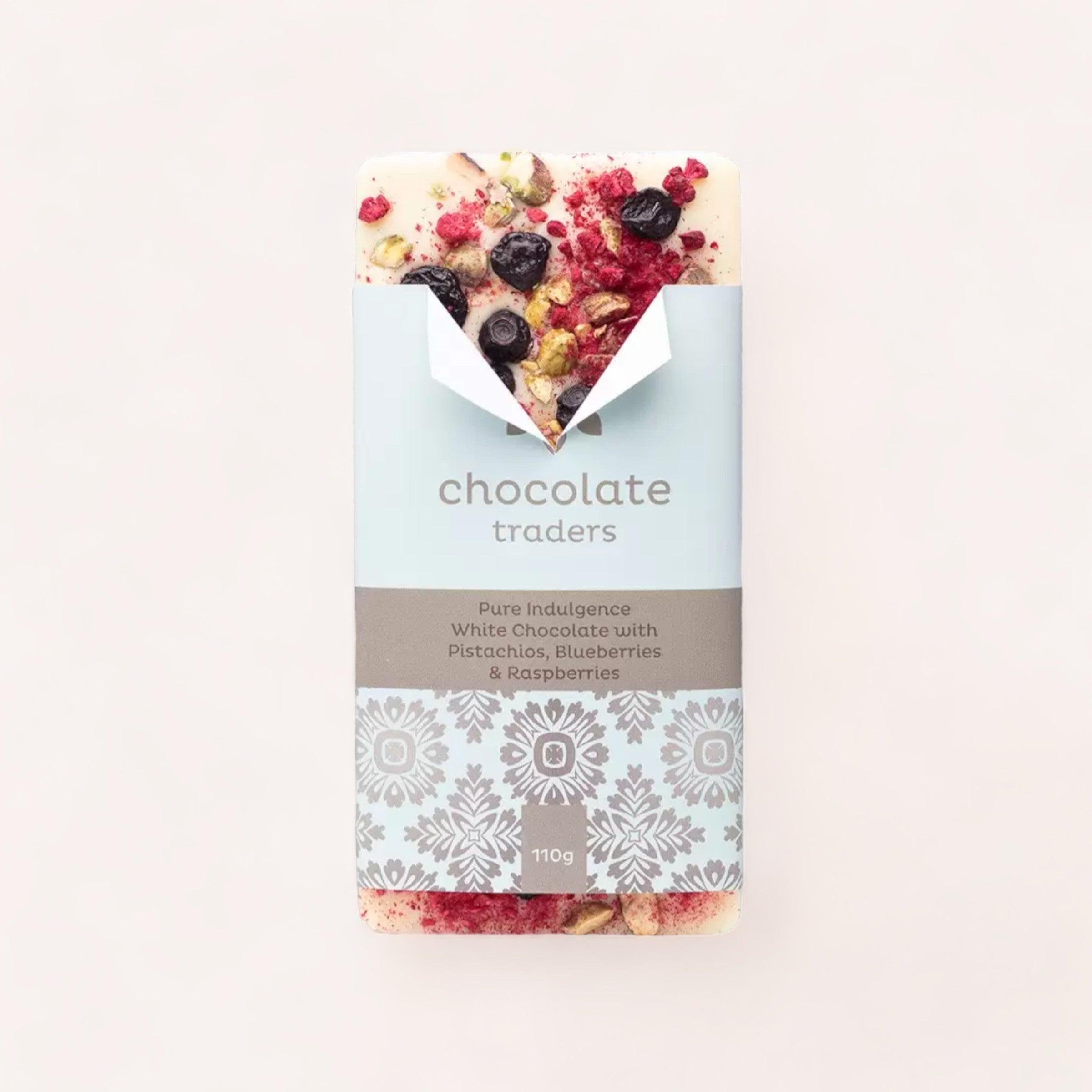 A gourmet Pure Indulgence Pistachios, Blueberries & Raspberries white chocolate bar by Chocolate Traders, presented in stylish packaging, perfect as a gift from New Zealand.