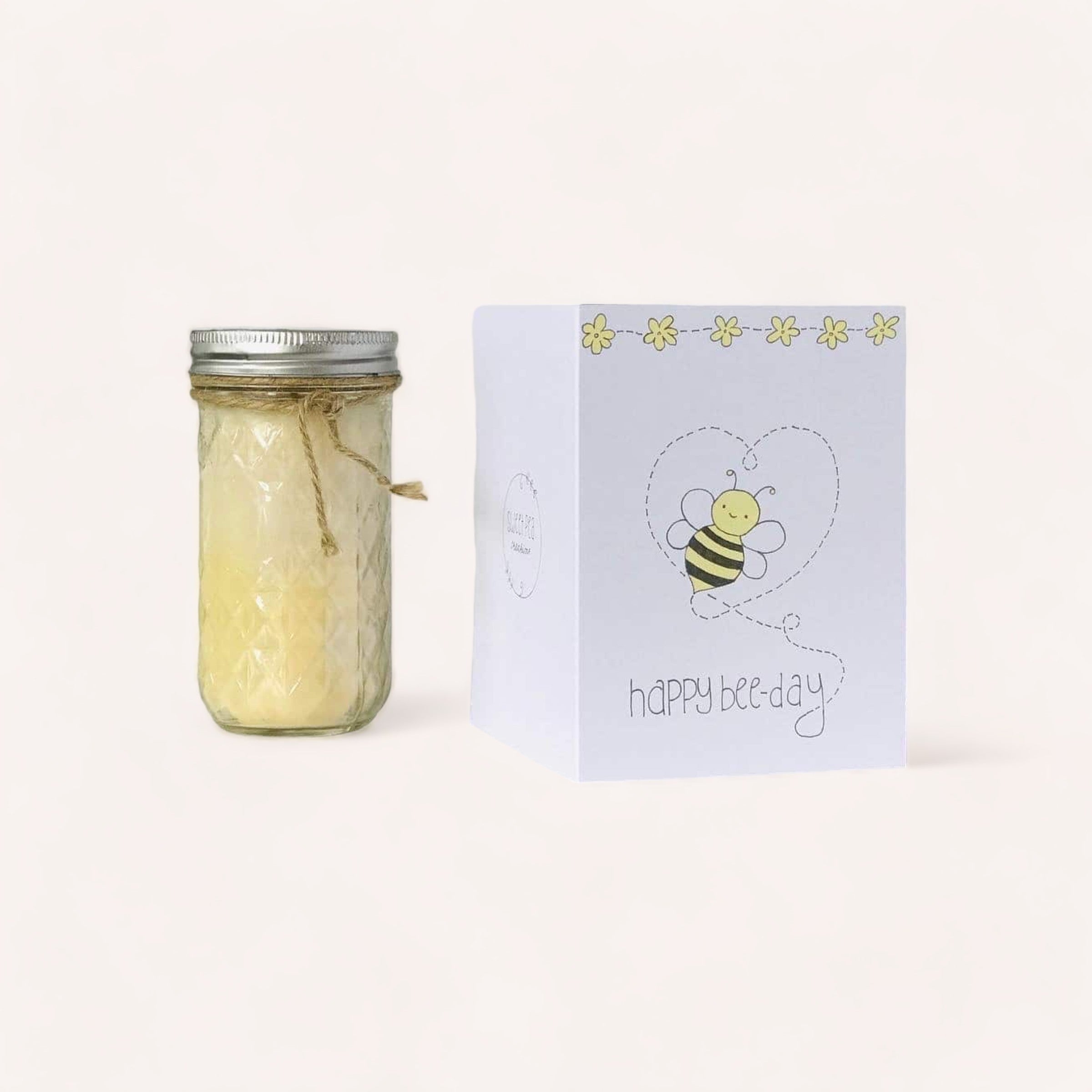 A jar of honey tied with twine paired with a Happy Bee-Day Birthday Card from Sweet Pea Creations featuring a cute bee illustration and the pun "happy bee-day" on a light background.
