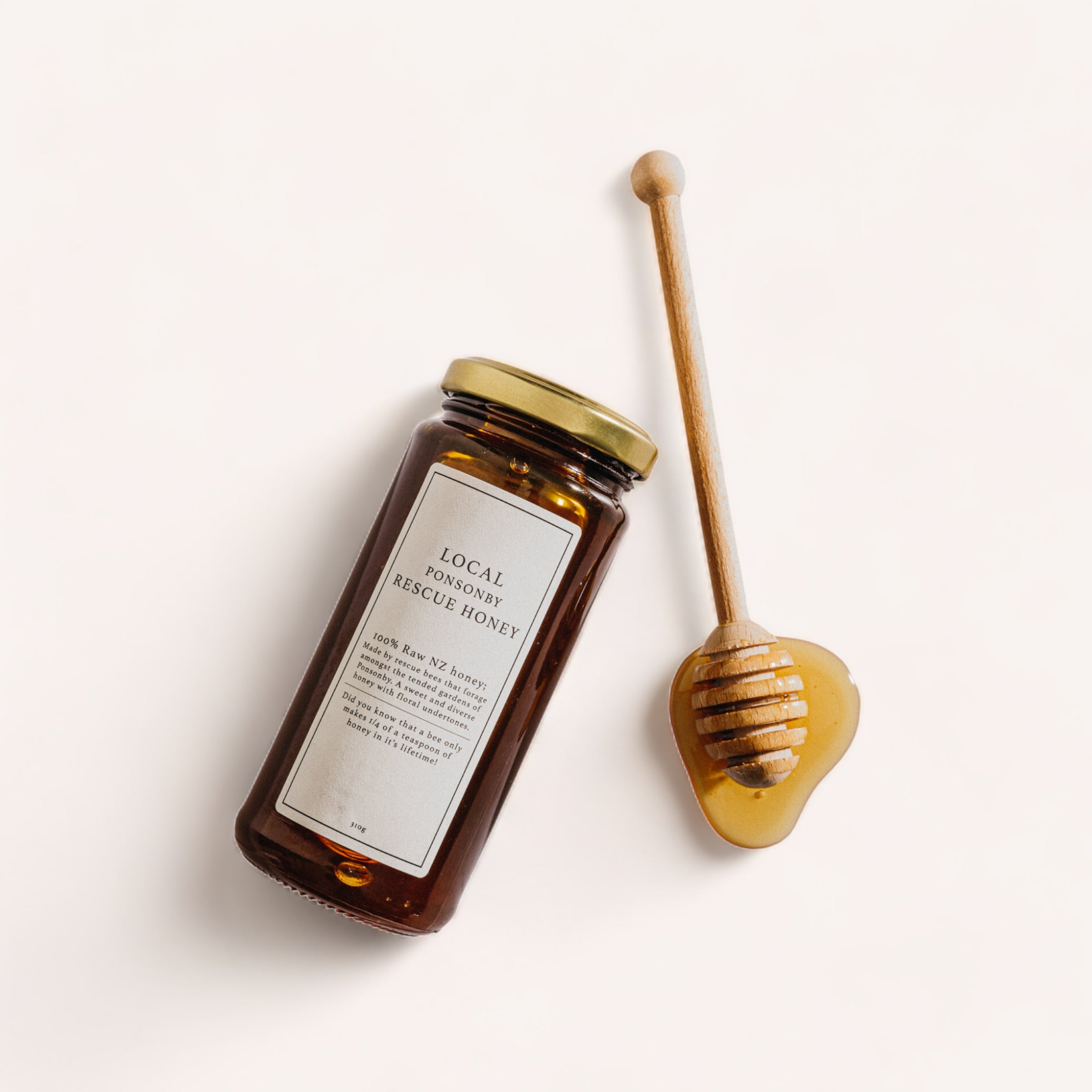 A jar of Ponsonby Rescue Honey by Bees Up Top with a wooden honey dipper on a white background.