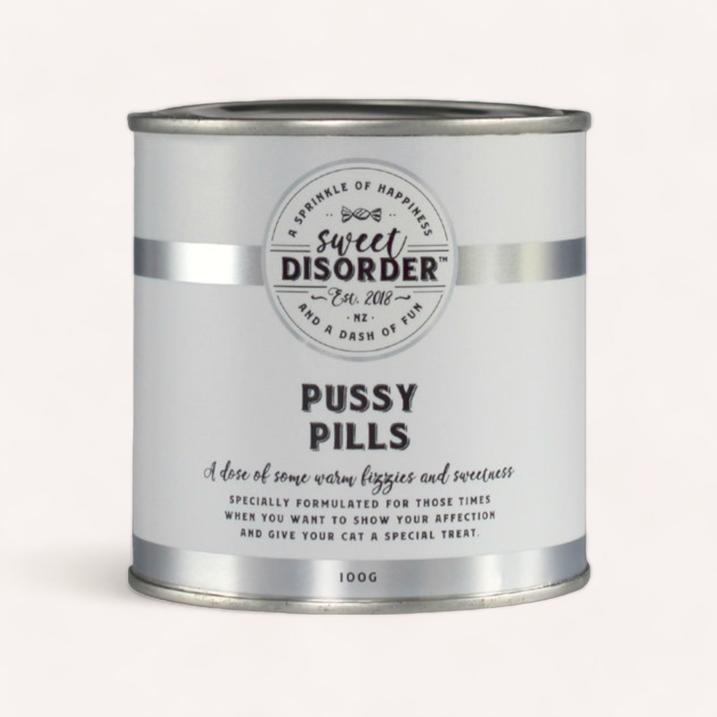 A cylindrical tin labeled "Pussy Pills Cat Treats by Sweet Disorder" containing "a sprinkle of happiness, love, and feline arrogance" designed as a whimsical gift product for cat owners.