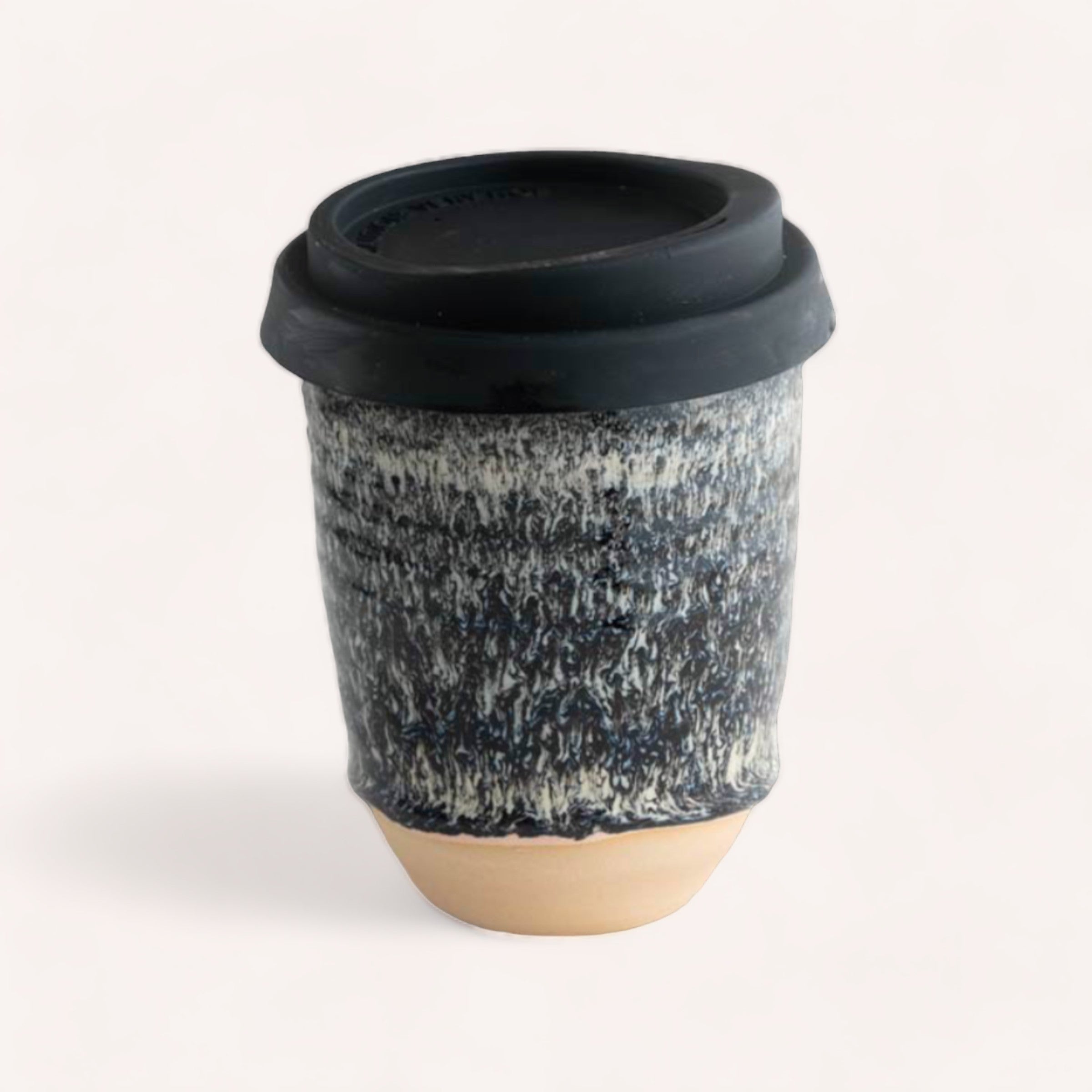 A stylish handcrafted Ceramic Keep Cup by Sam Mayell sporting a textured black and white design, made from NZ sourced stoneware by Queenstown pottery, with a black lid, placed against a neutral background.