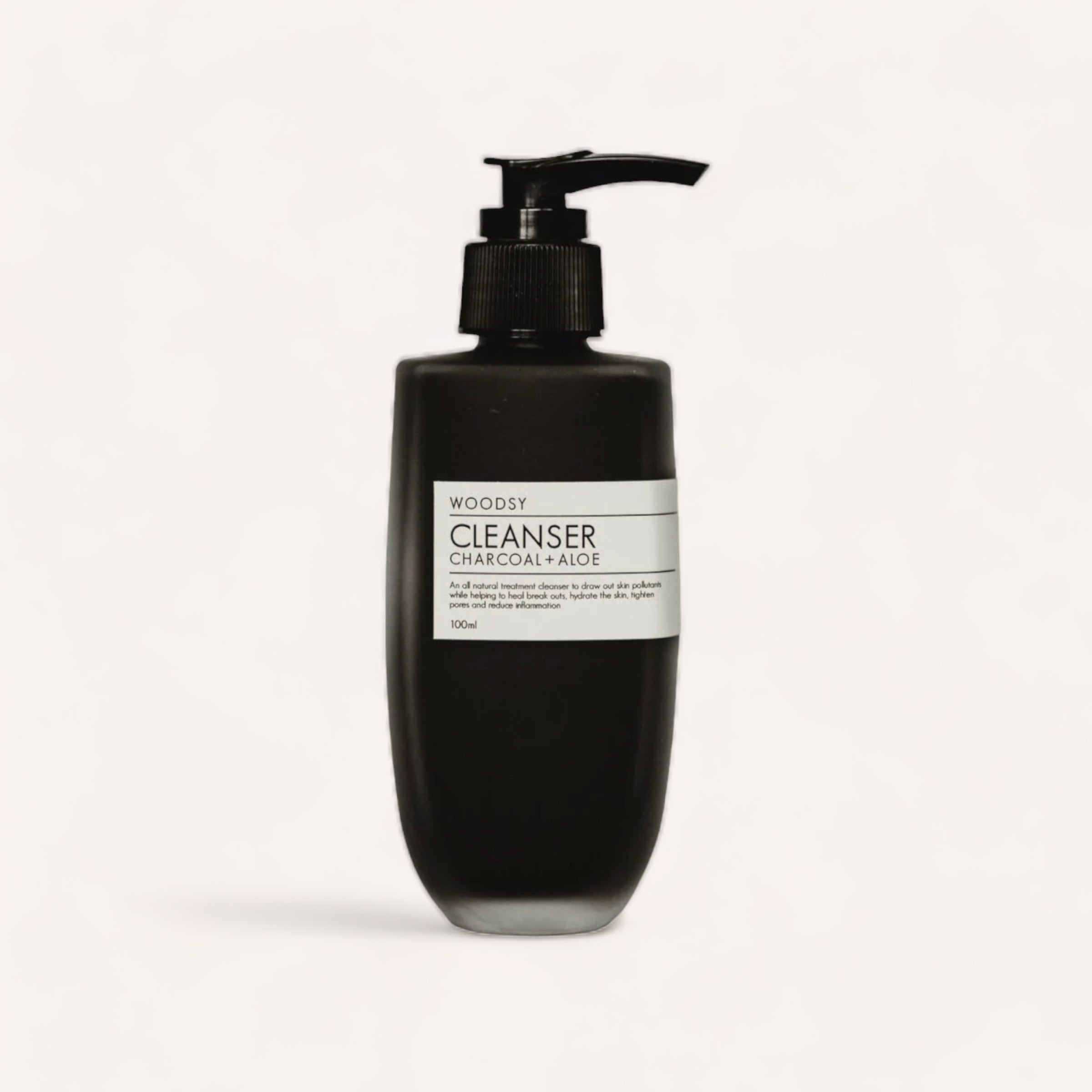 A black pump bottle of Cleanser - Charcoal & Aloe by Woodsy Botanics, presented against a clean white background.