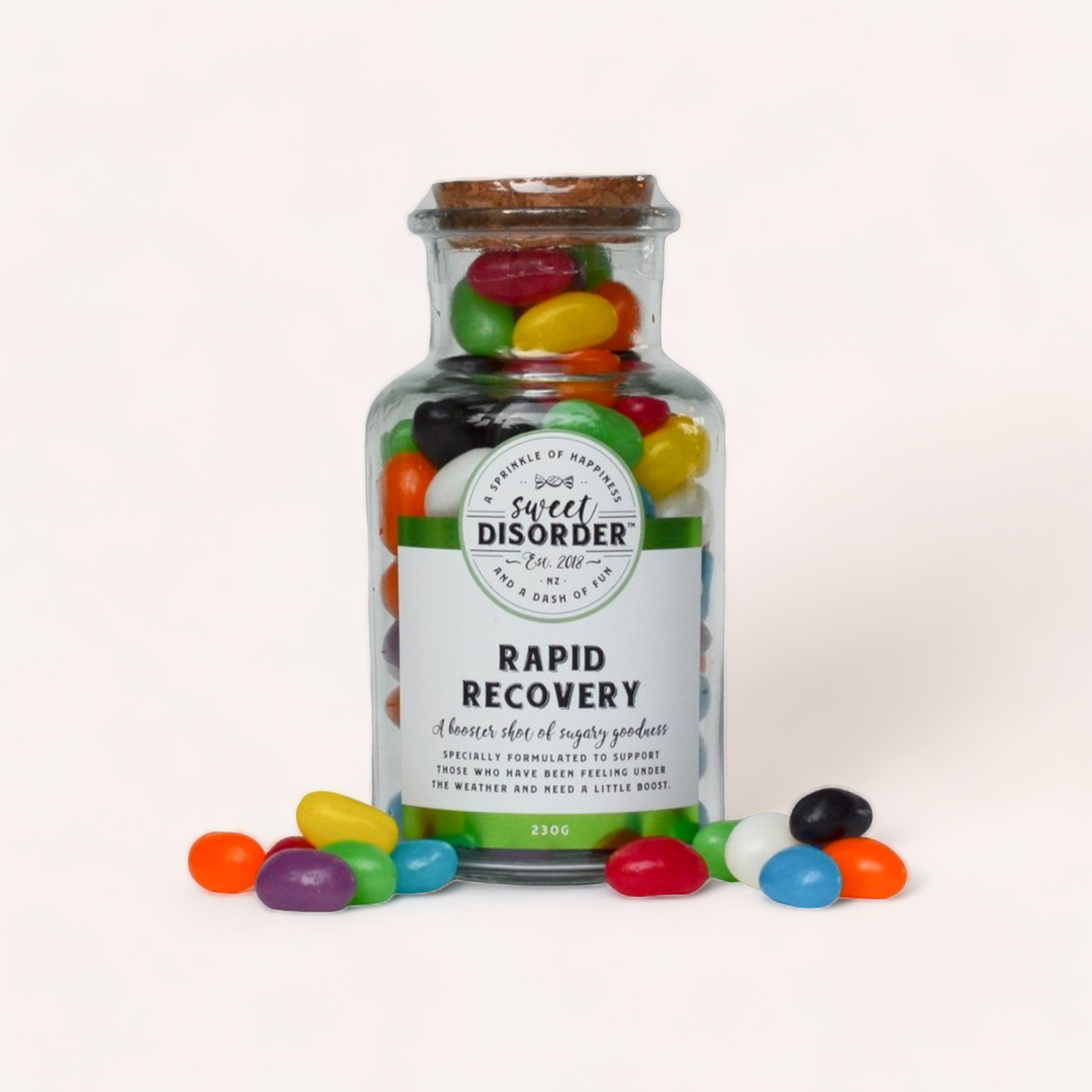 A colorful assortment of jelly beans spilling out of a Sweet Disorder "Rapid Recovery Lollies" prescription-styled candy jar, perfect for those feeling under the weather, against a white background.