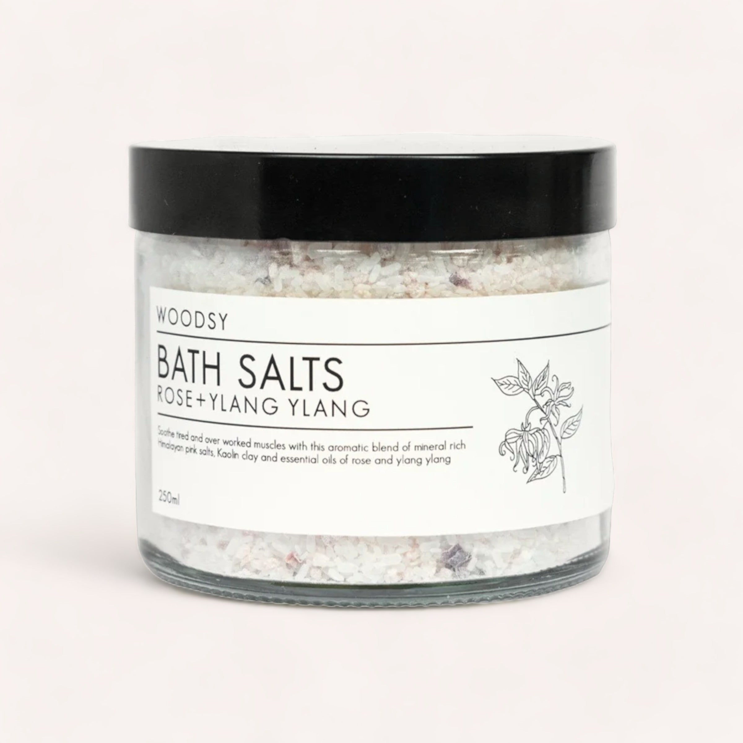 Clear glass jar of Bath Salts - Rose & Ylang Ylang labeled "Woodsy Botanics" with organic essential oils in a simple, elegant design.