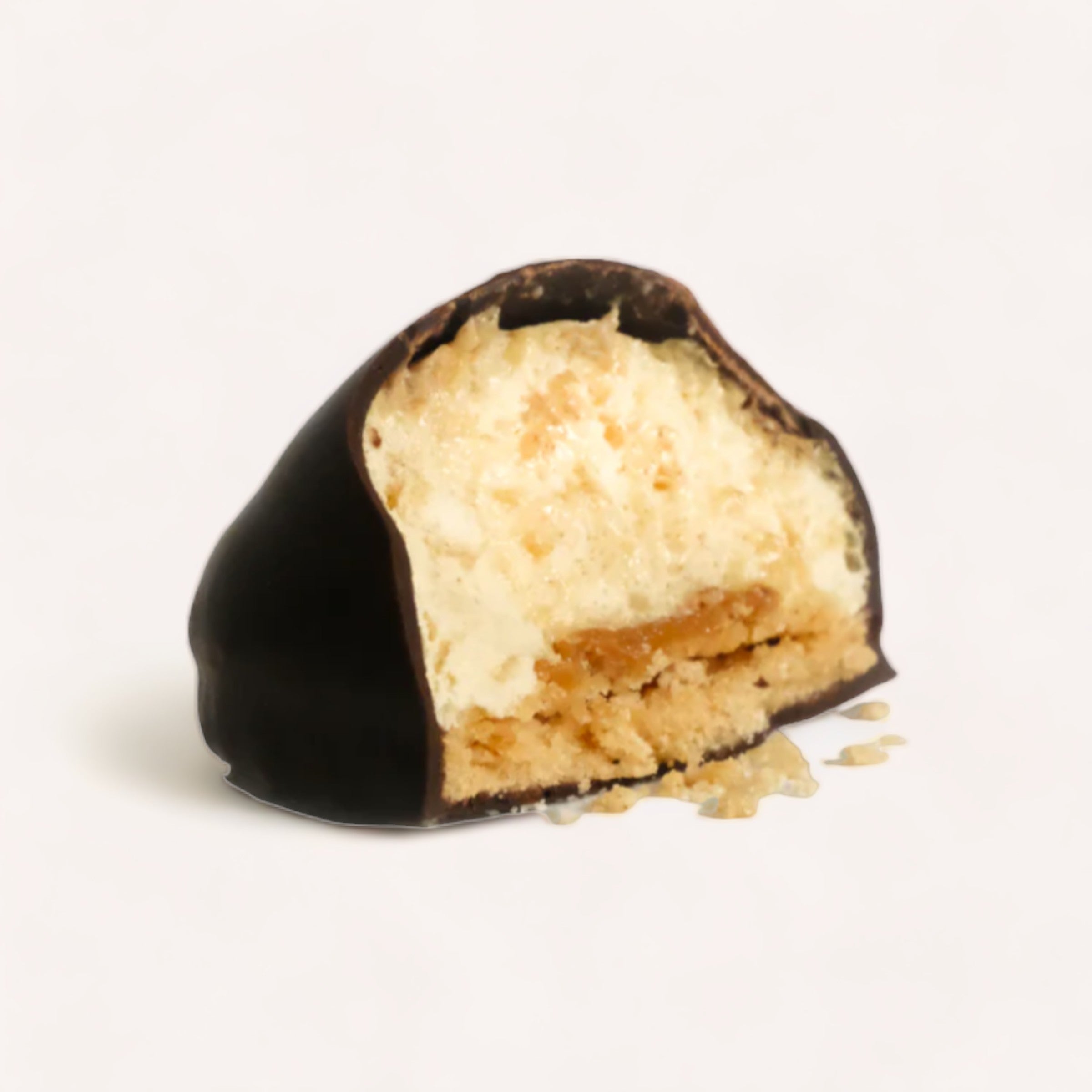 A cross section of Baron Hasselhoff's Salted Caramel Mallow Puffs, a gluten-free, chocolate-covered dessert with a layered filling, showing a gooey caramel center and soft, crumbly cookie-like layers on a plain white background.