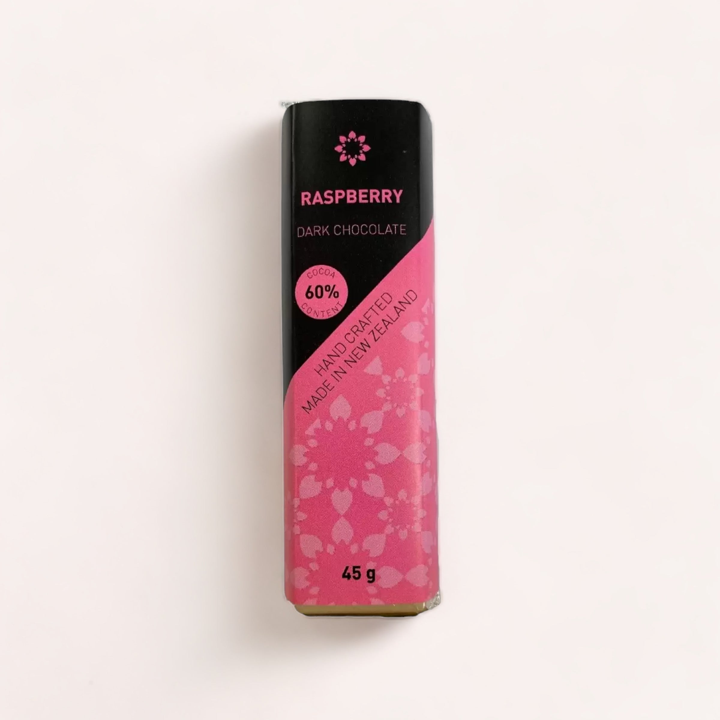 A bar of Raspberry Chocolate bar with 60% cocoa, handcrafted and fair trade, product of New Zealand, weighing 45 grams, wrapped in a packaging with a pink and heart design by Chocolate Traders.
