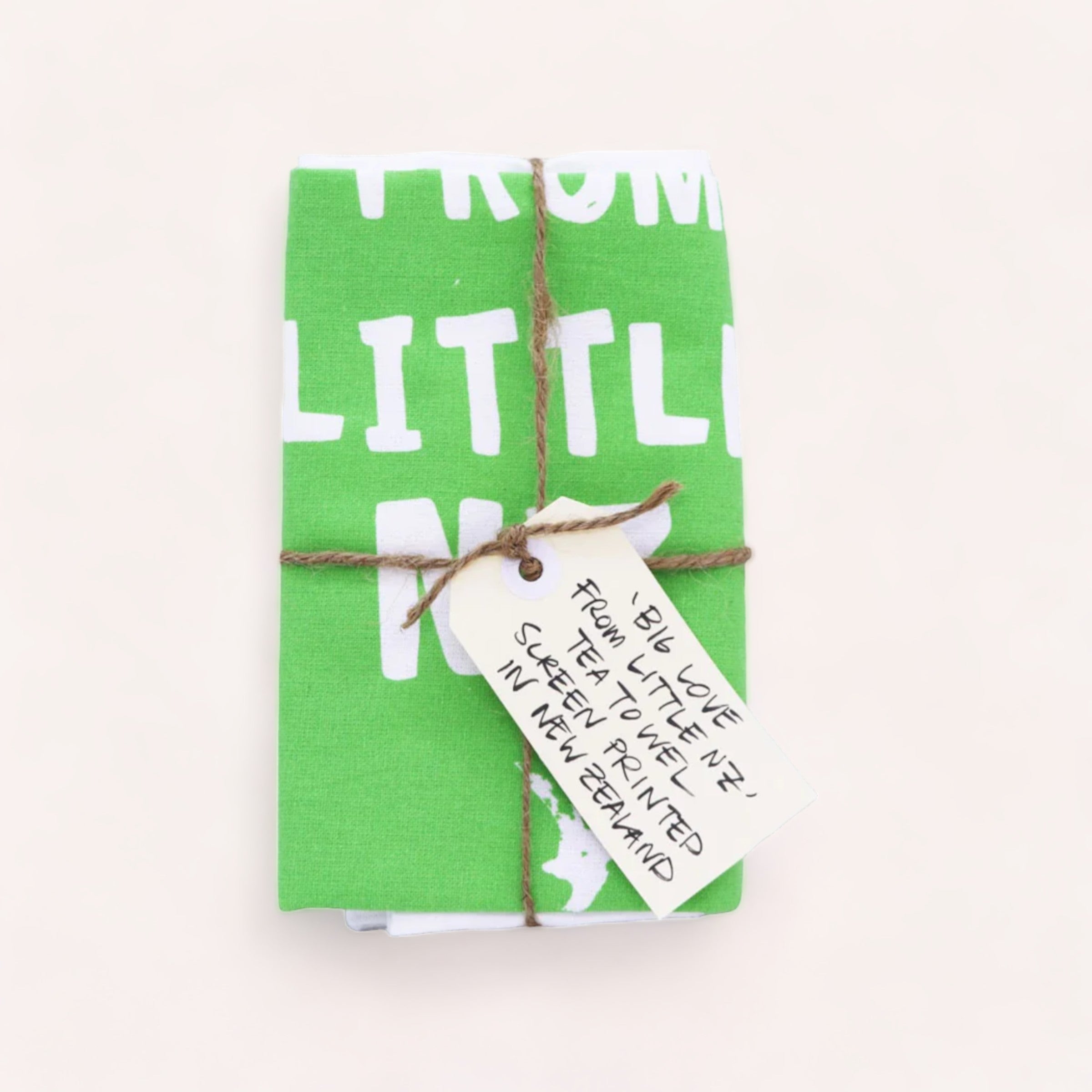 A neatly wrapped gift in green fabric with white lettering, tied with a rustic string and a handwritten gift tag, encasing a Tuesday Print Big Love from little NZ Tea Towel.