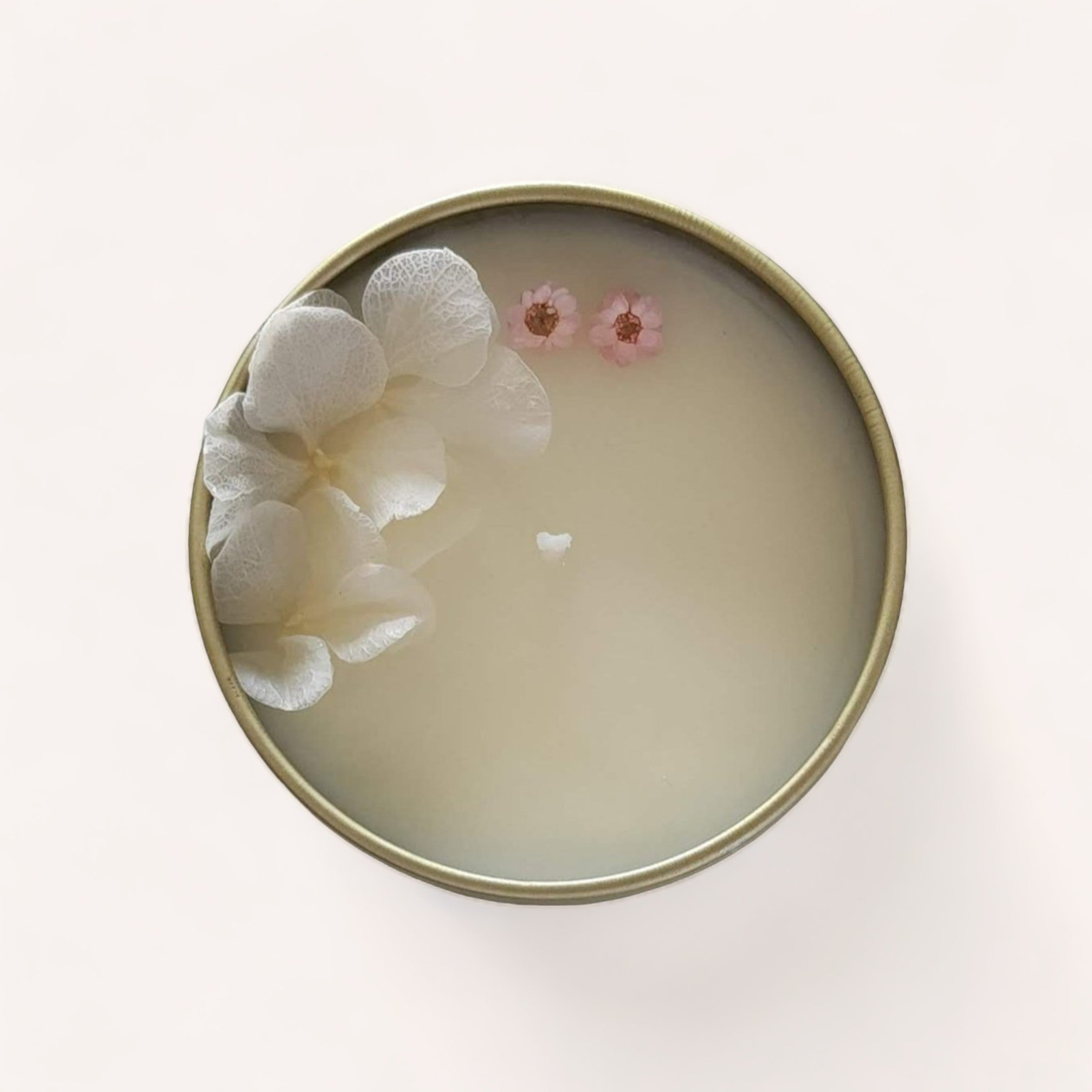 A serene bowl of water with delicate flowers gracefully floating on the surface, embodying tranquility and simplicity, beside a Coconut + Lime Candle by Wix's Lane Co infusing the air with its soothing aroma.