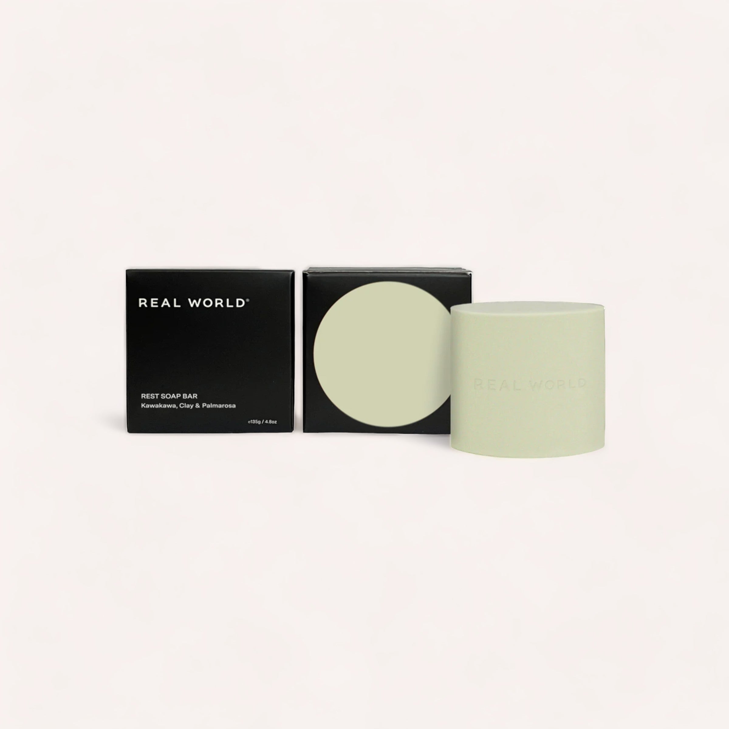 Elegant personal care products on display featuring minimalist design packaging with a Kawakawa, Clay & Palmarosa soap bar by Real World and a container for restorative cleansing.