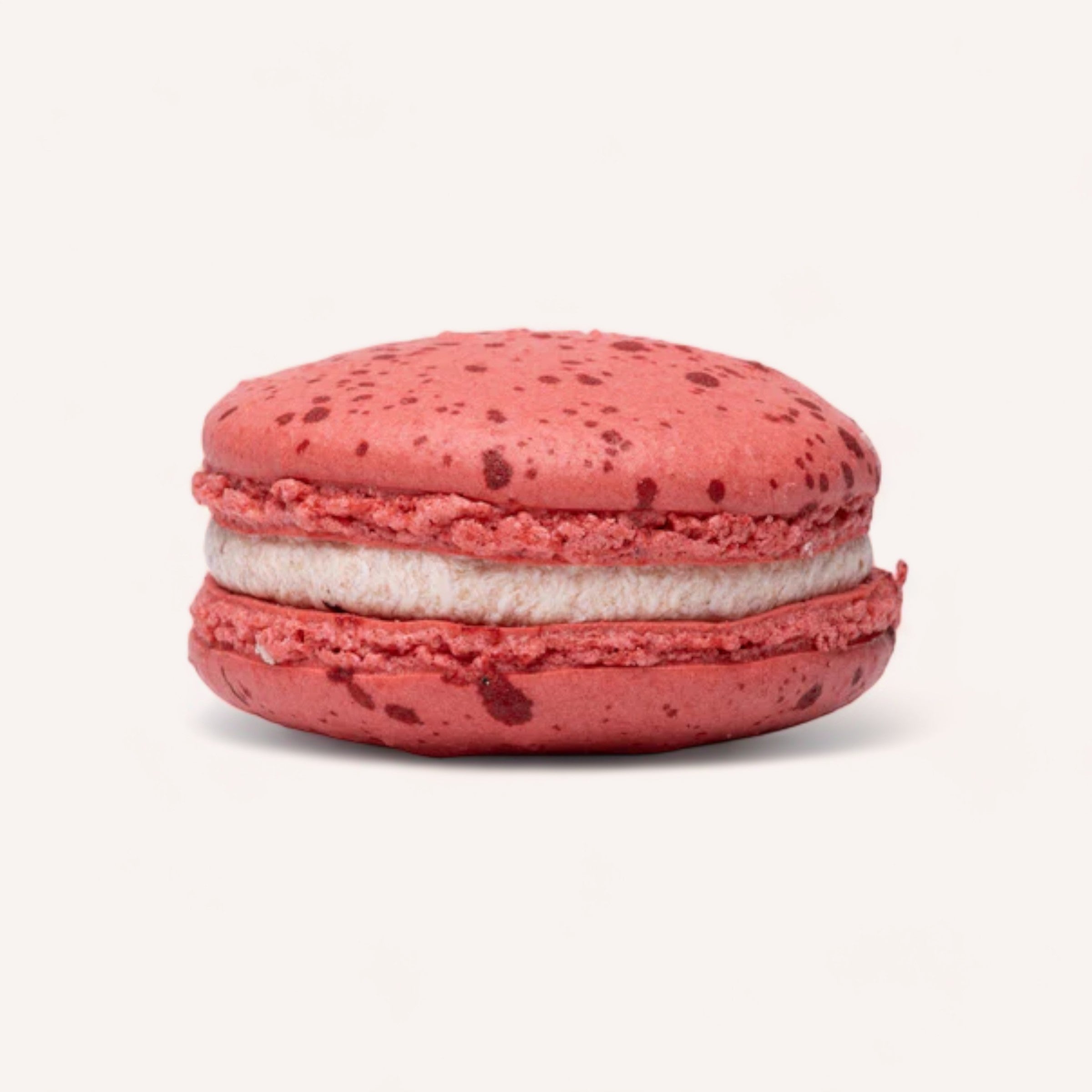 A vibrant red handmade Box of 6 Macarons by J'aime les Macarons with a creamy filling, showing its delicate texture and inviting appearance.