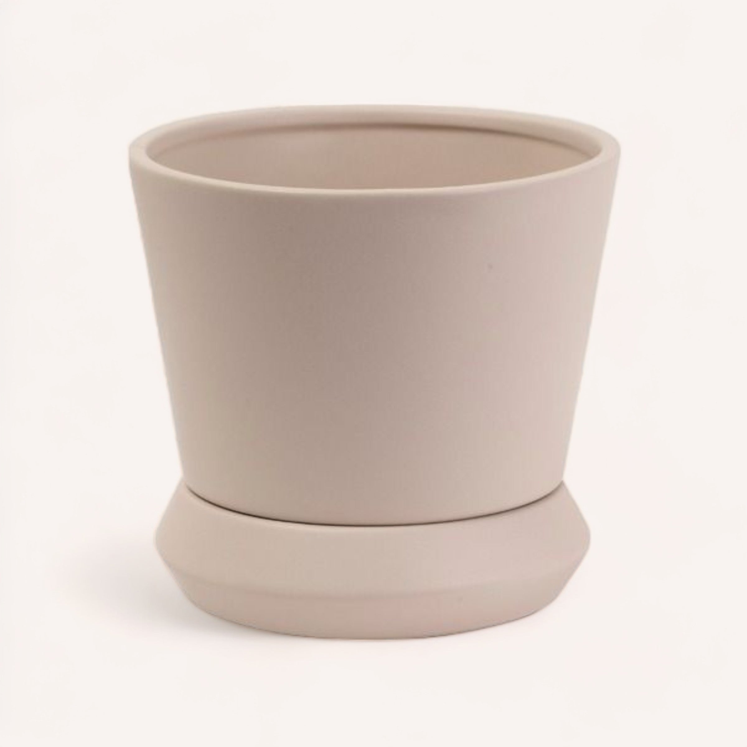 Sentence with replaced product and brand name: Simple beige Hamburg Planter by PottedNZ with a matching saucer and drainage hole on a white background.