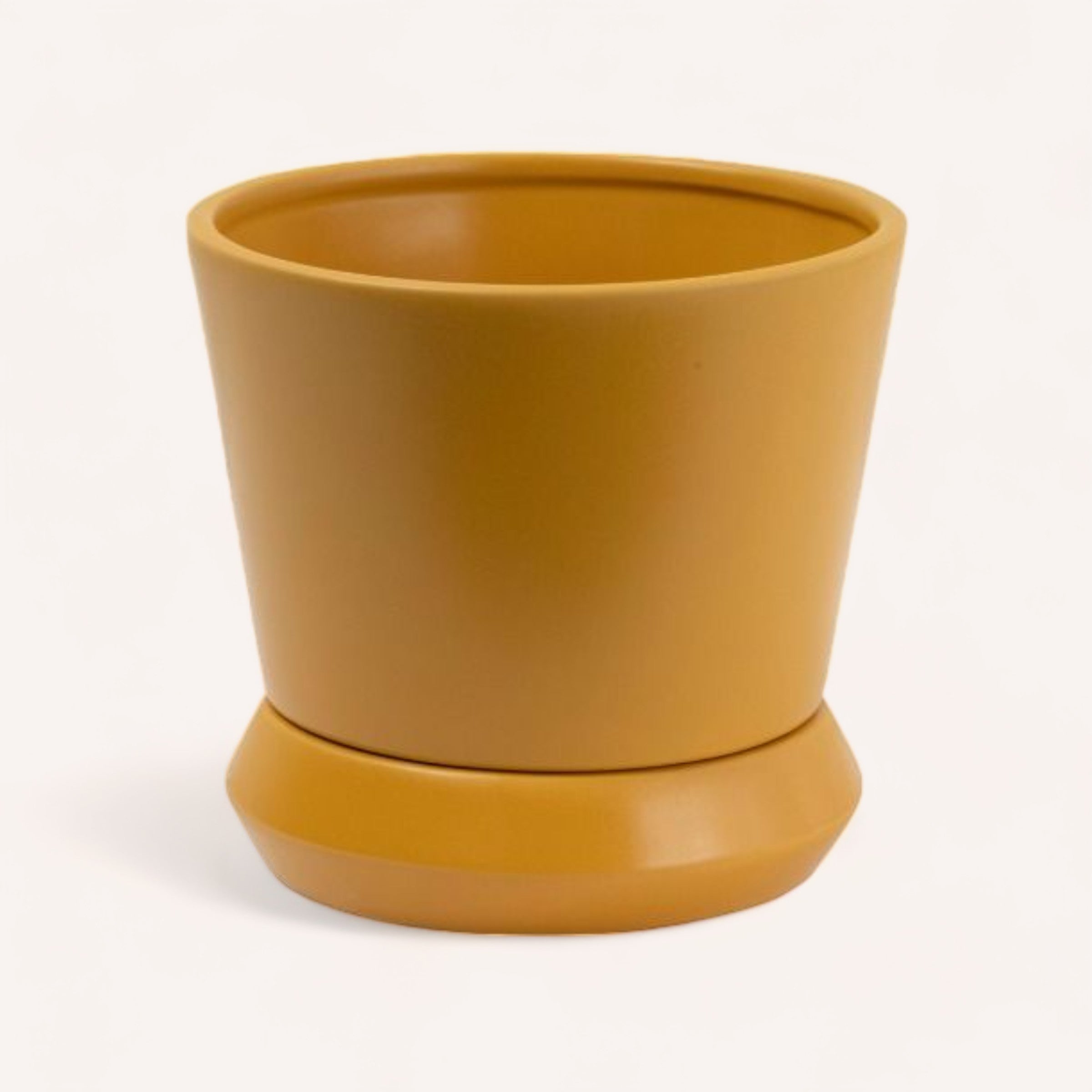 A simple Hamburg Planter by PottedNZ in terracotta color stoneware with a matching saucer and a drainage hole, set against a white background.
