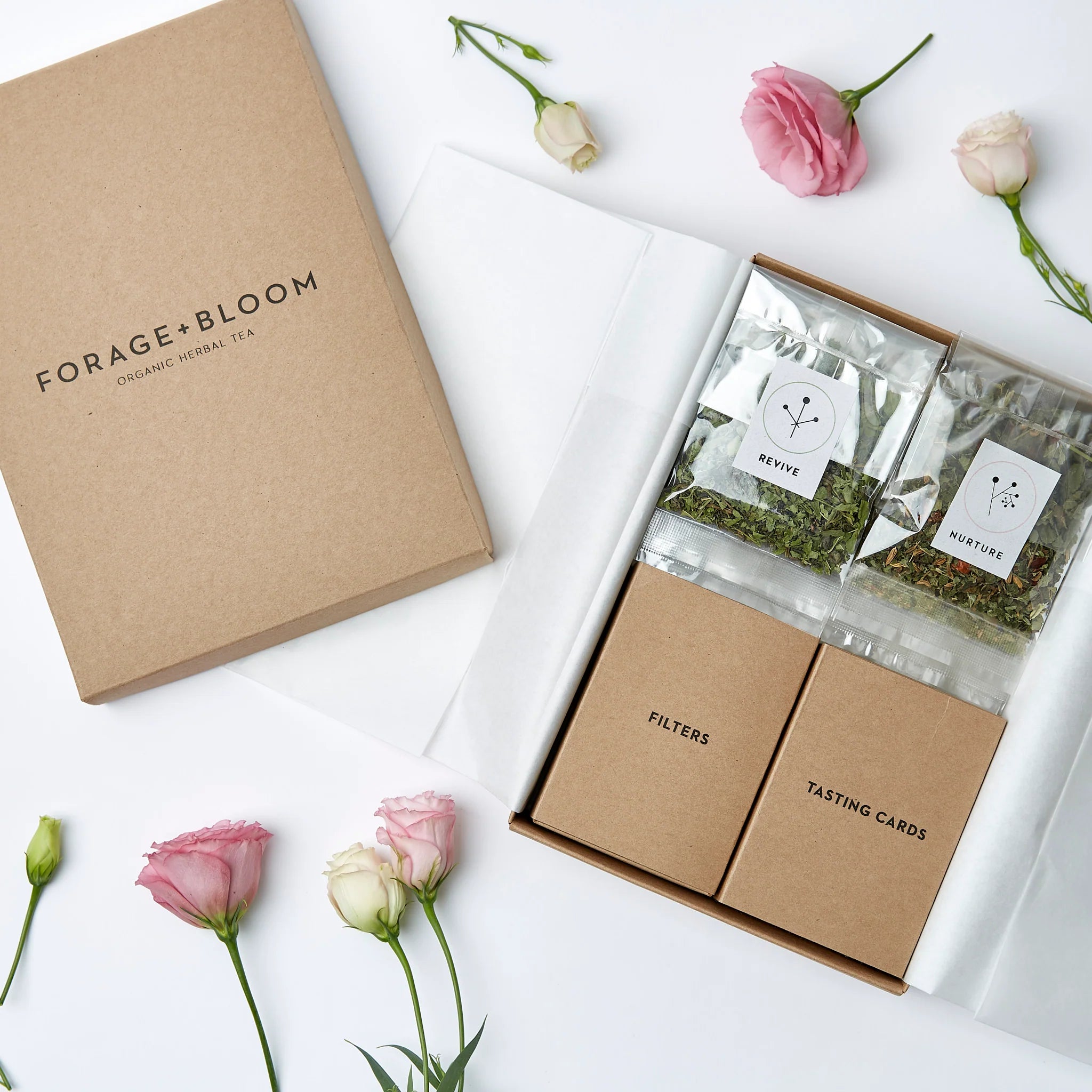 Elegant tea tasting set from Tea Testing Box Set by Forage + Bloom with organic herbal tea blends, accompanied by tasteful packaging and delicate flowers.