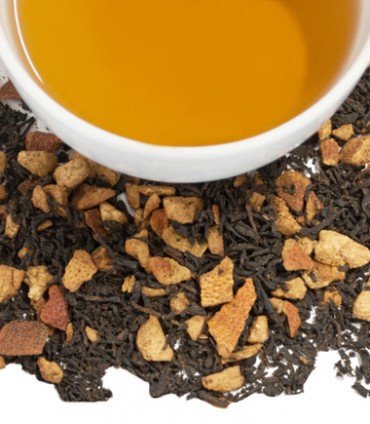 A cup of Hot Cinnamon Sunset Tea Tagalong surrounded by Harney & Sons loose leaf tea and spices, suggesting a warm and spicy brew.