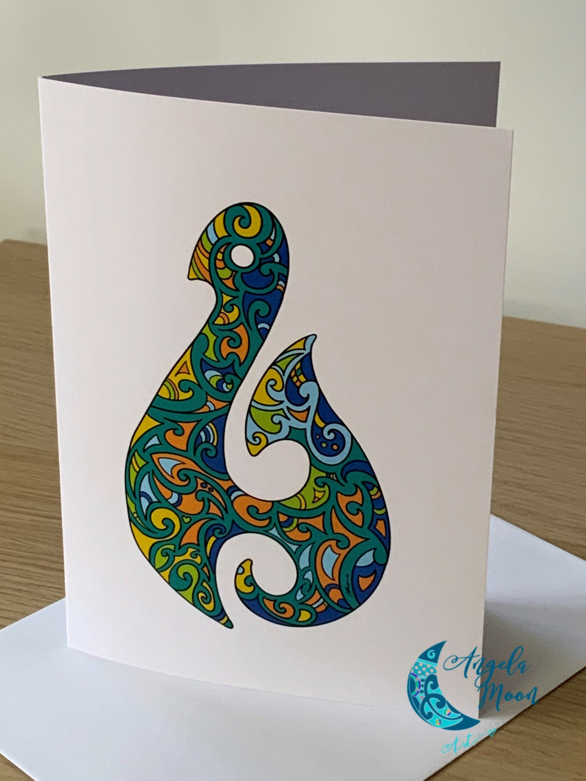 A Matau Card by Angela Moon Art presenting an intricate paisley cut-out design, part of a Multibuy offer, is standing on a table, accompanied by an envelope.