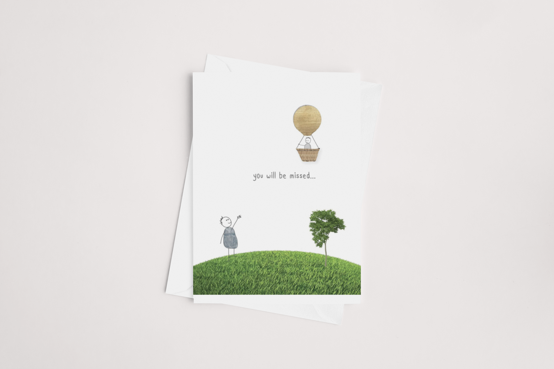 A You Will Be Missed Card featuring a simple illustration of a lone figure standing under a tree, gazing at a hot air balloon ascending into the sky, with the heartfelt message "you will be missed..." printed by icandy.