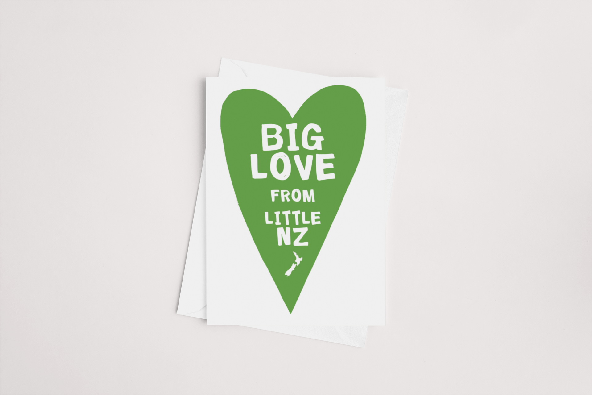A "Big Love from Little NZ Card" product of Tuesday Print, featuring a large green heart with the text "big love from little nz," incorporating a silhouette of New Zealand at the bottom of the heart, symbolizing affectionate
