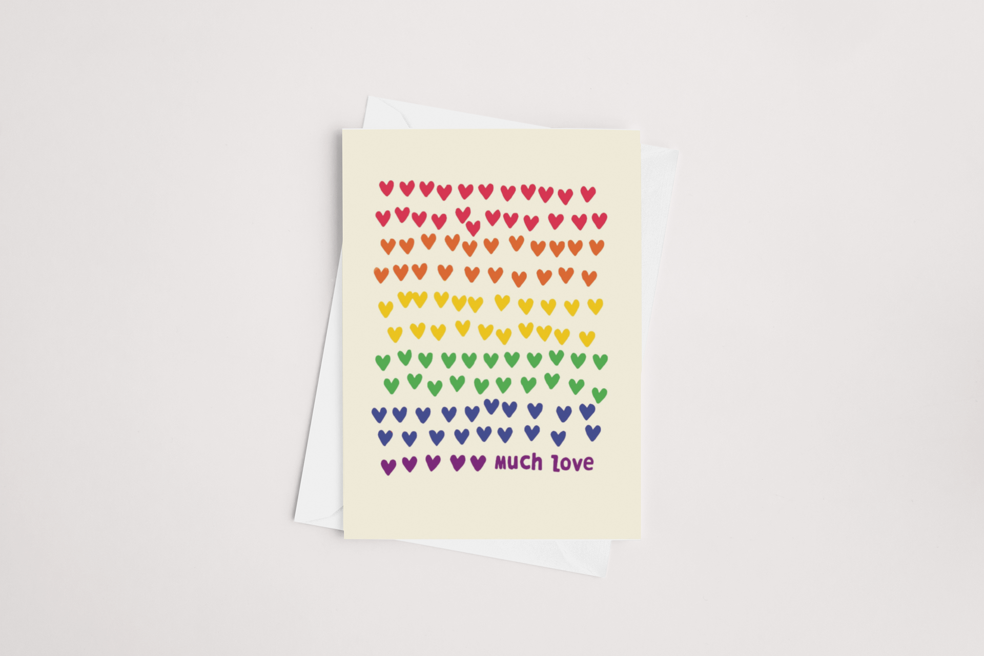 A cheerful Rainbow Hearts Card by Tuesday Print featuring rows of colorful hearts in a rainbow spectrum with the words "much love" at the bottom, accompanied by a white envelope against a clean, white background. This delightful multib