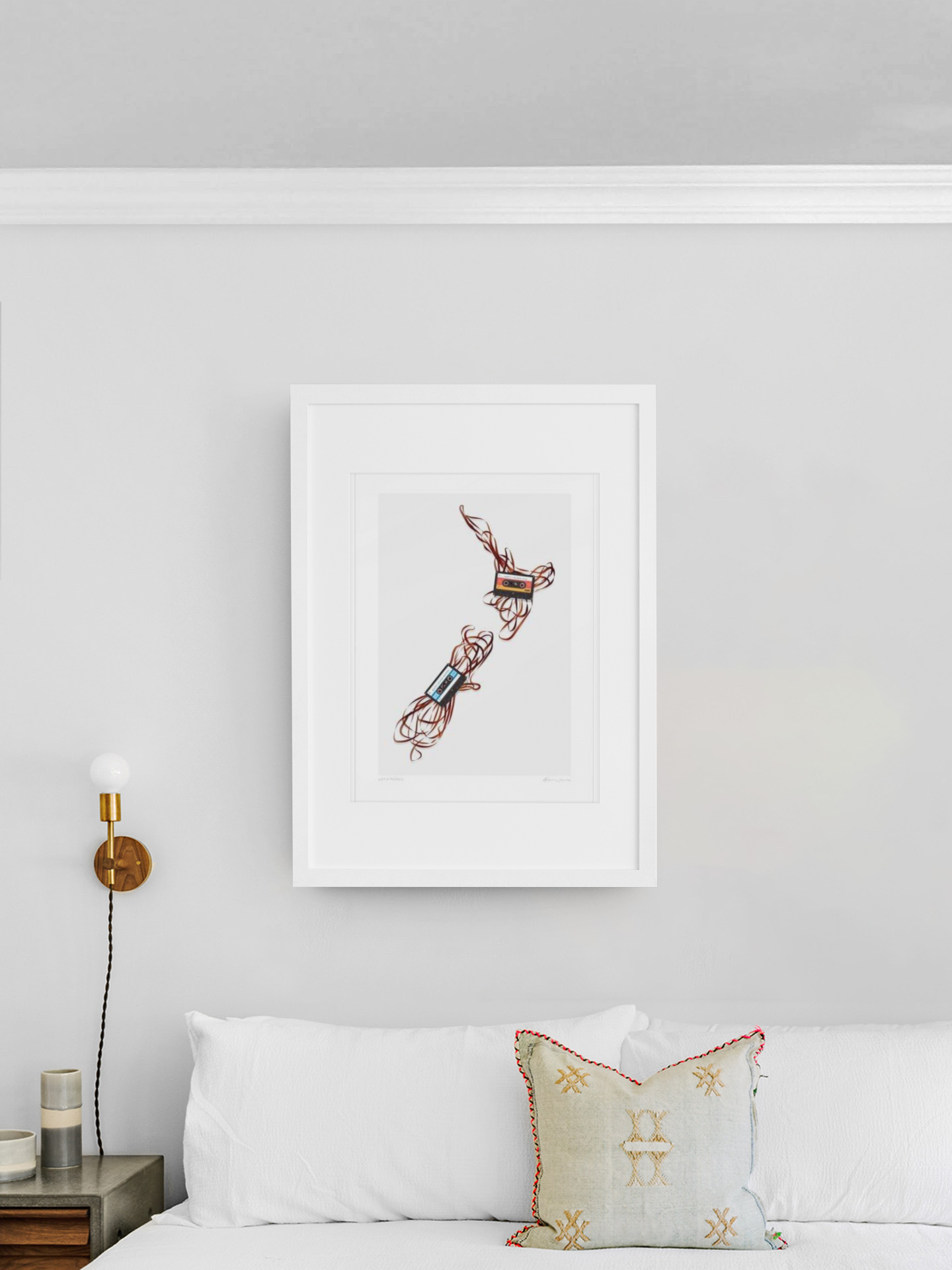 Modern art piece featuring Get a Pencil by Glenn Jones, an abstract, linear design in red against a white backdrop, elegantly framed and displayed on a clean, white wall above a cozy bed with plush pillows, illustrating the vibes of old.