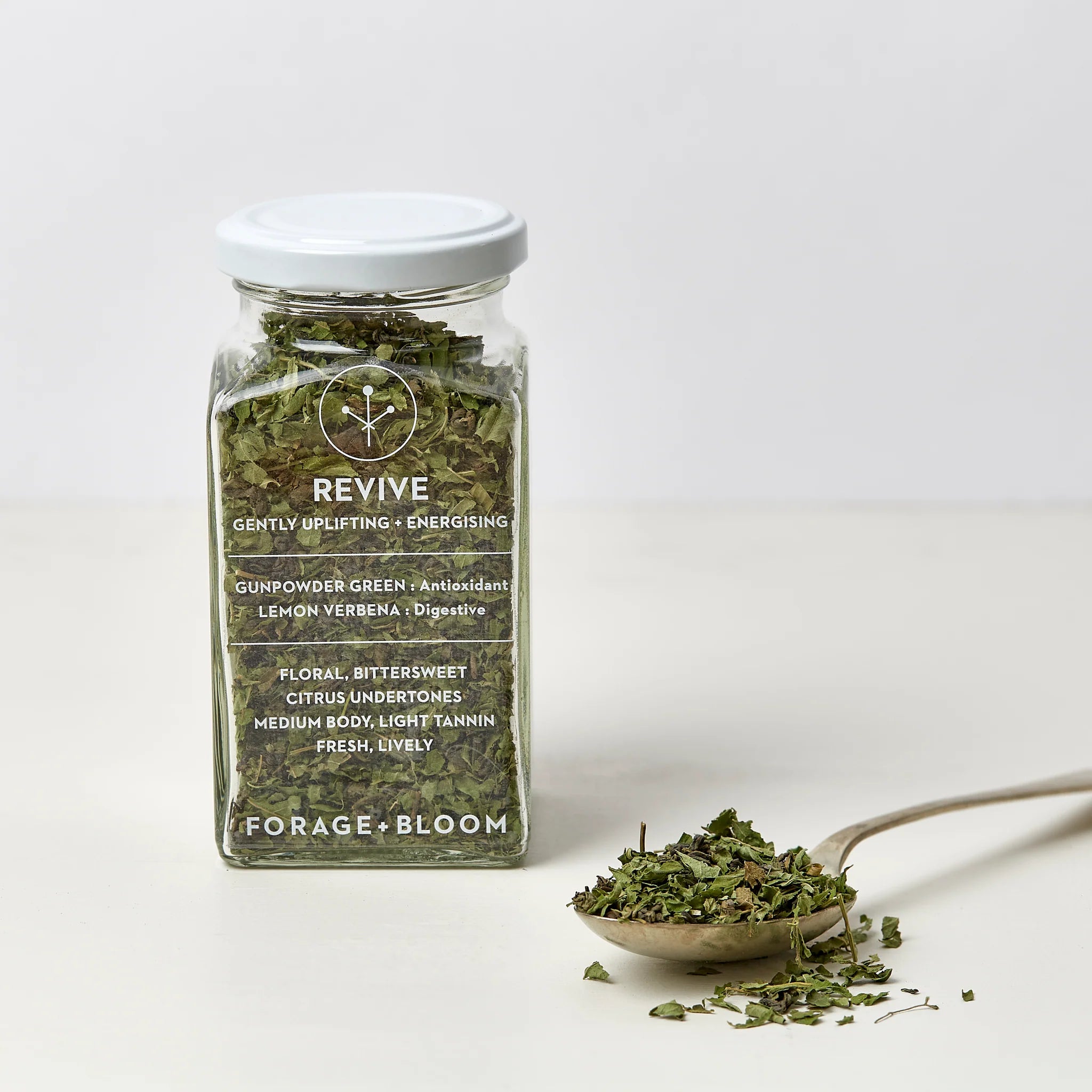 A glass jar filled with loose leaf tea, labeled "Tea for Two - gently uplifting, energising" with descriptors such as "gunpowder green, antioxidant, lemon verbena, citrus undertones," from giftbox co.