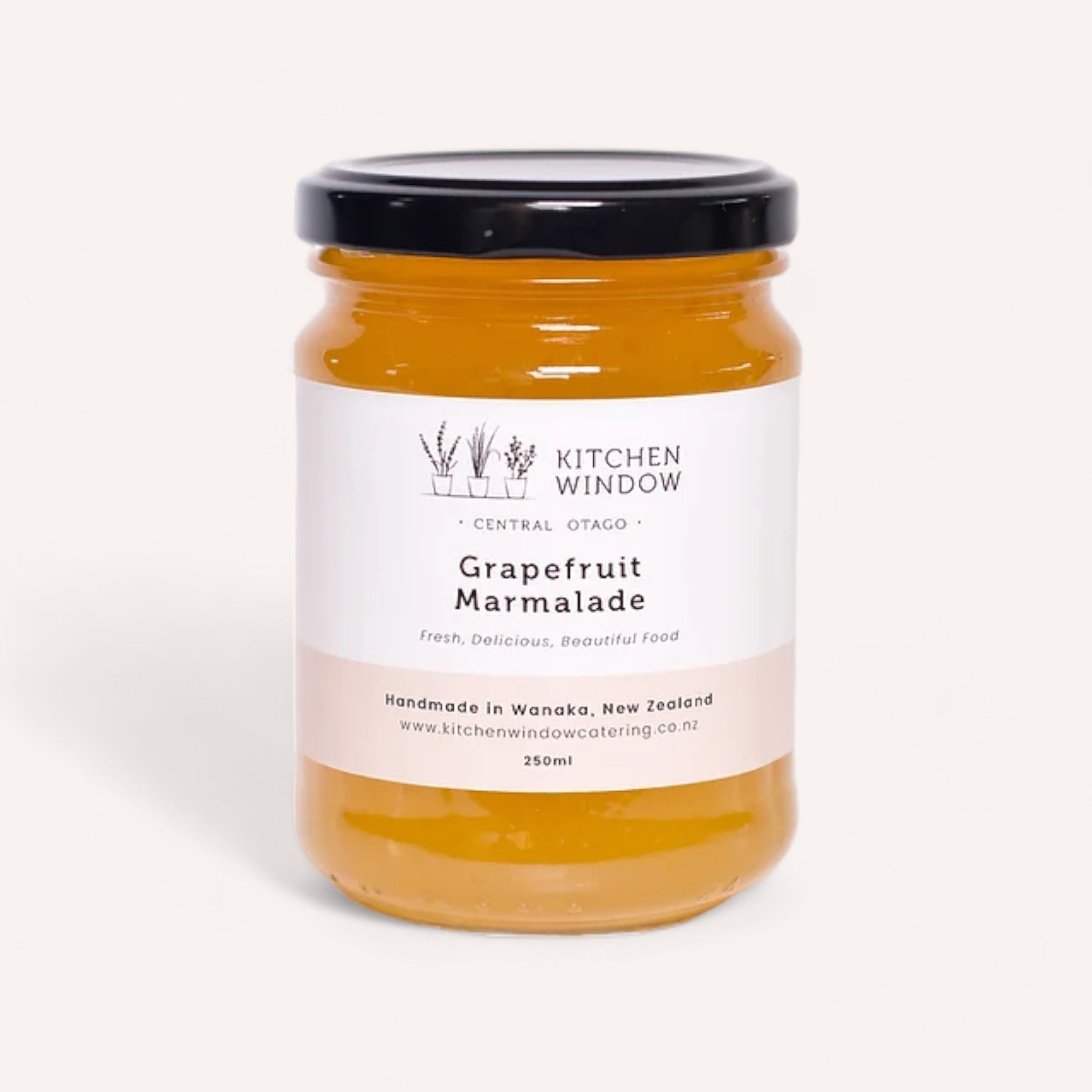 A 250ml jar of Grapefruit Marmalade by Kitchen Window, featuring a black lid and a white label. The label includes information stating it's handmade in Wanaka, New Zealand, and provides the website www.kitchenwindowcatering.co.nz.