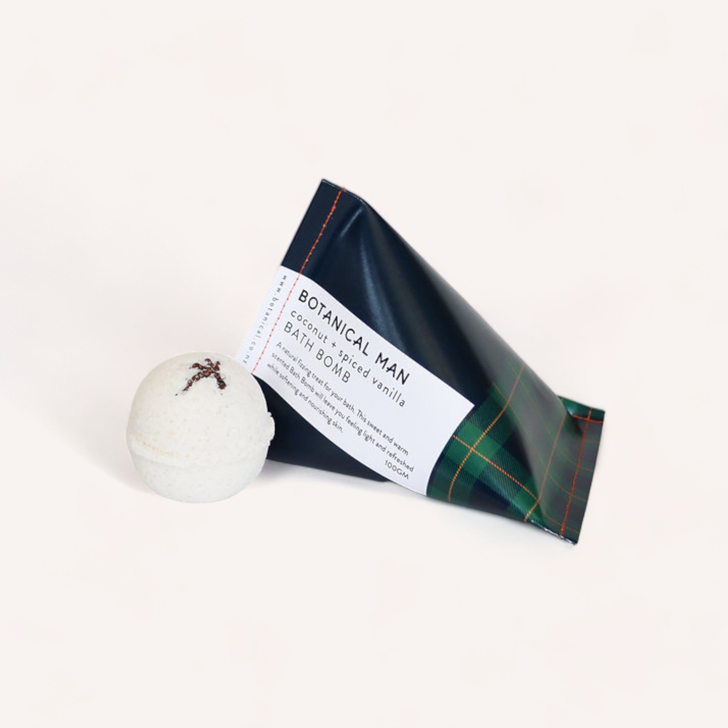 A Botanical Man Bath Bomb by Botanical Skin Care accompanied by its packaging that reads "botanical man - fragrant coconut & vanilla bath bomb" on a clean white background.